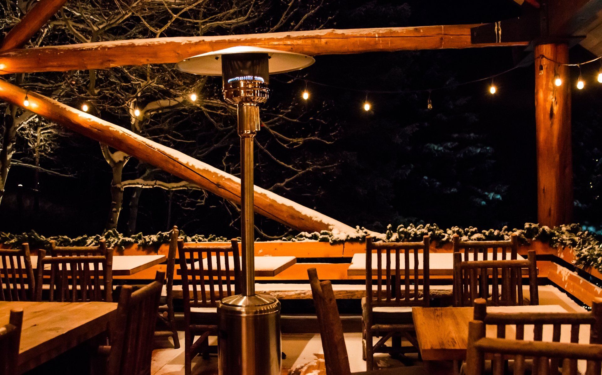 A snow-covered outdoor dining area with propane heaters