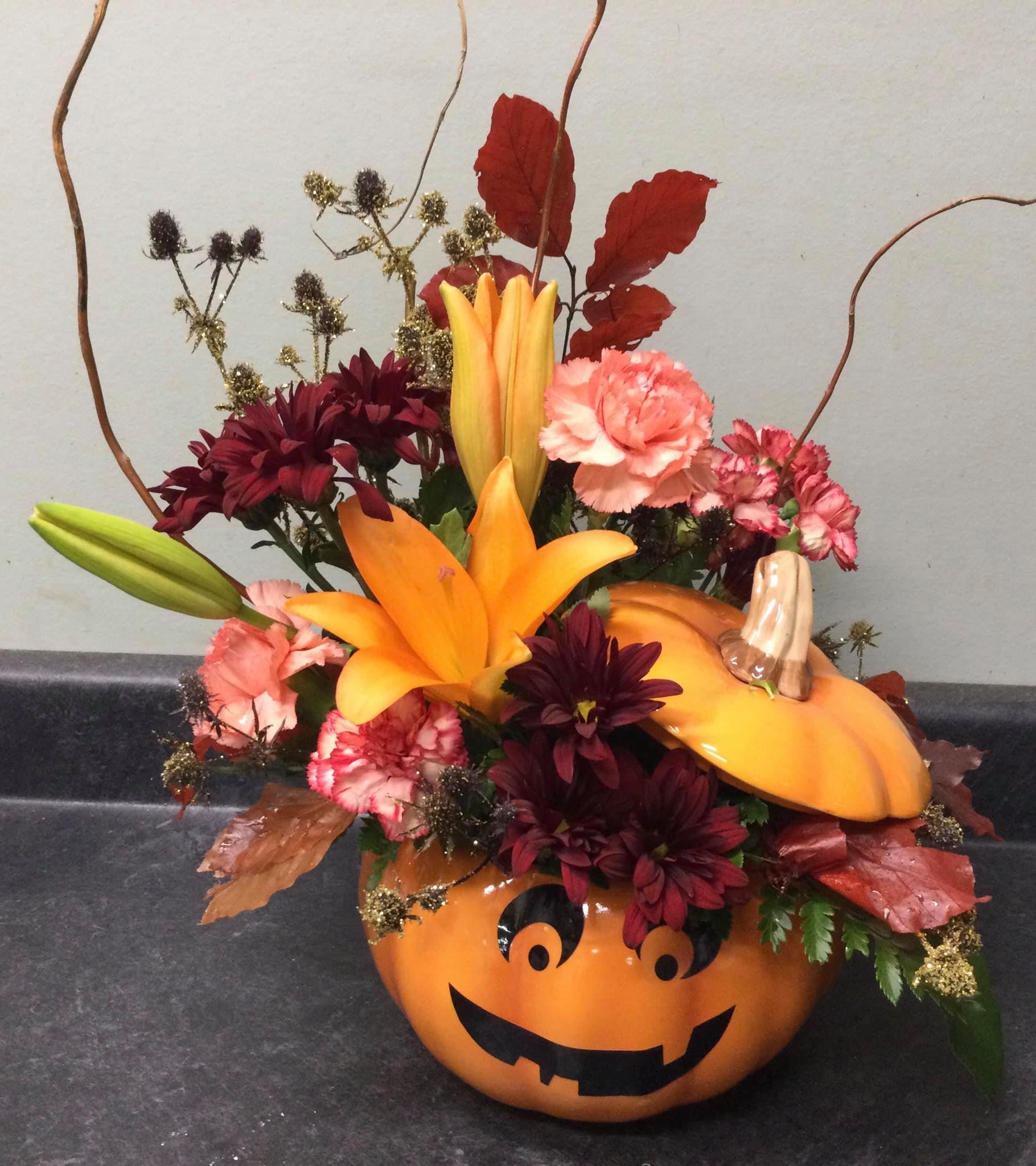 Floral arrangement of daylilies and carnations in a jack-o-lantern ceramic jar