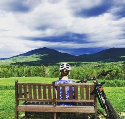 A mountain biker taking a break to enjoy the view by sitting on a bench