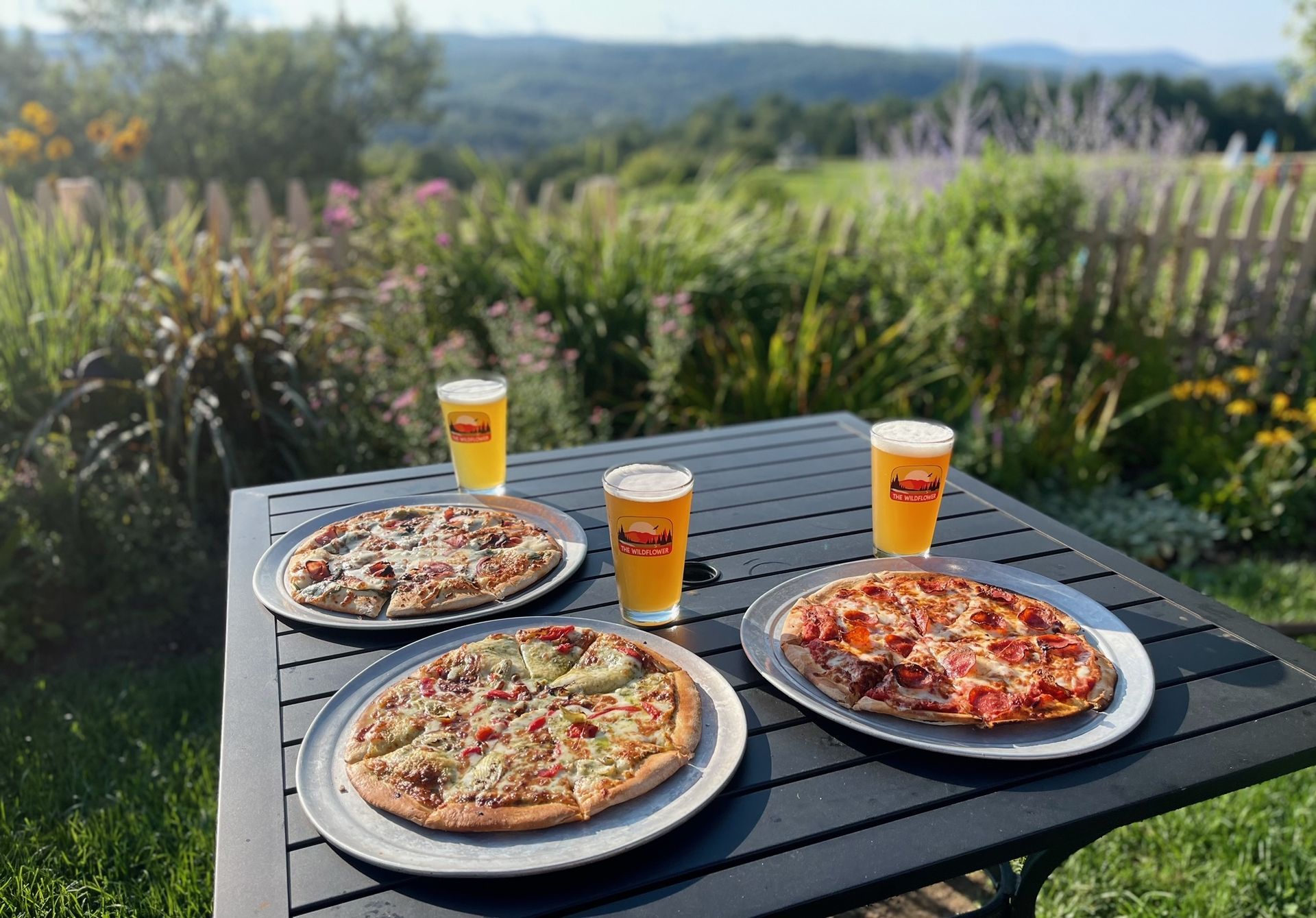 Pizza and beer on an outdoor table.