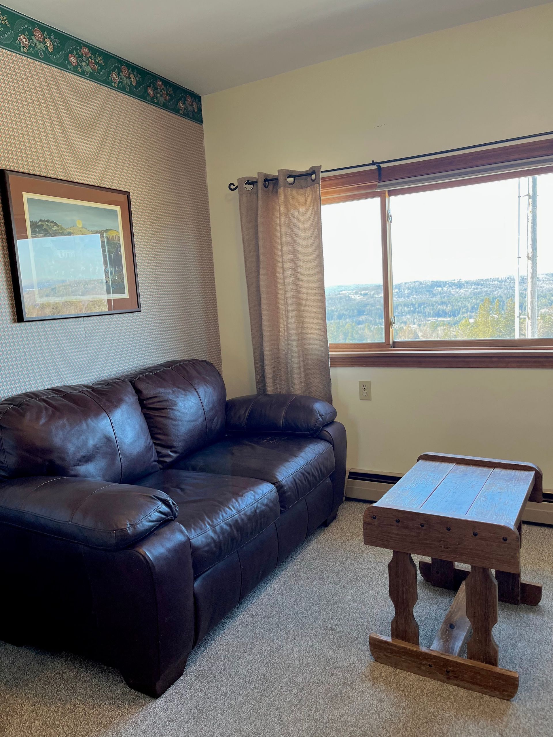 A living room with a brown leather couch and a wooden table.