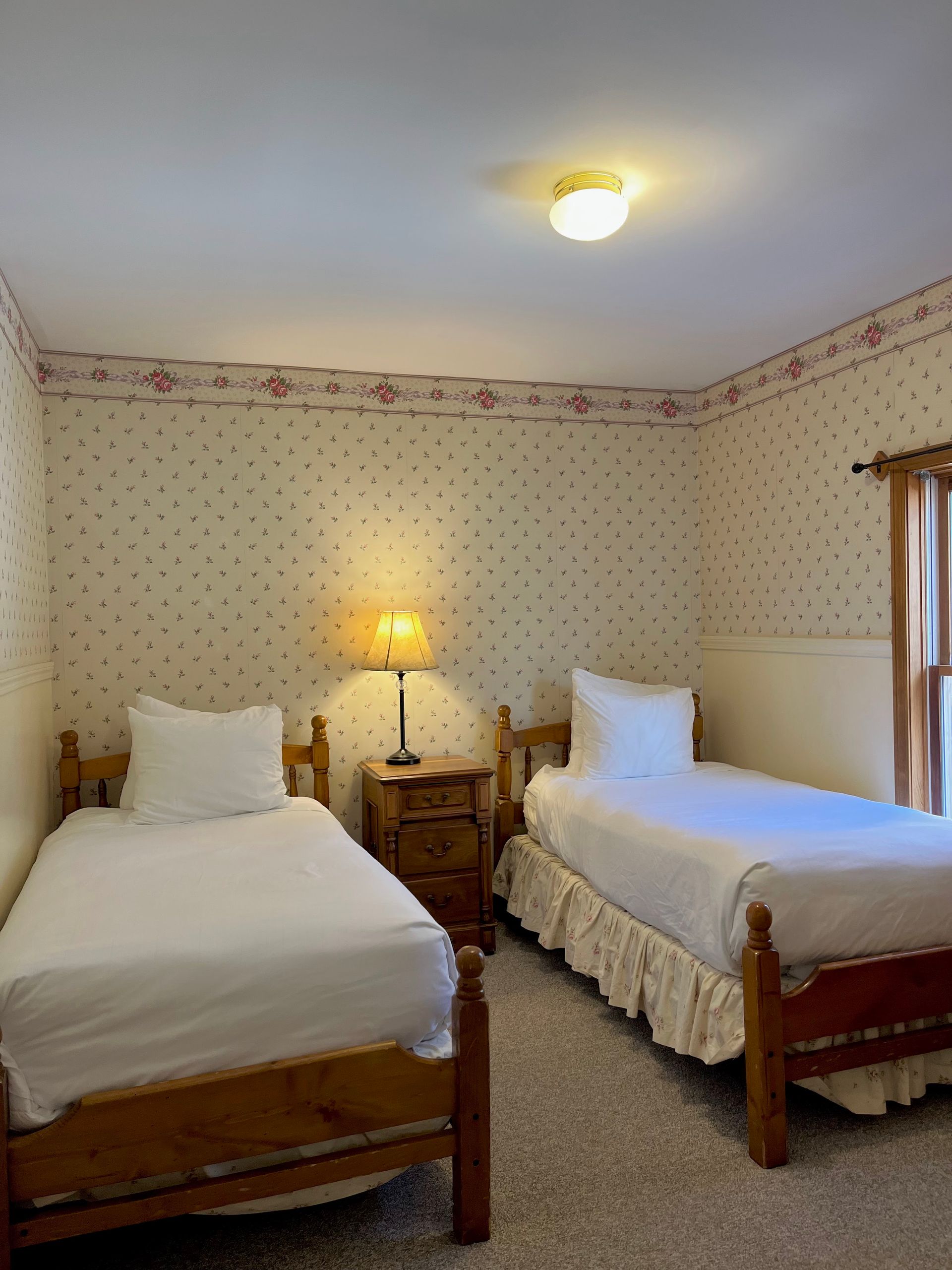 A bedroom with two twin beds and a lamp.