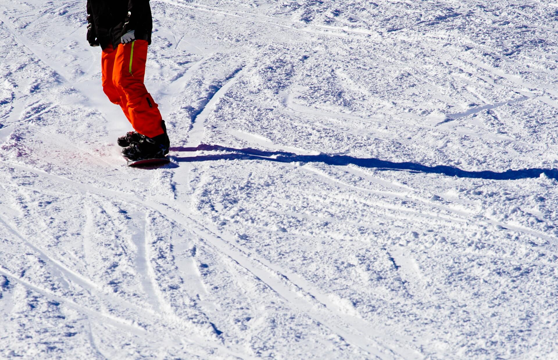 Person snowboarding down a groomed mountain trail.
