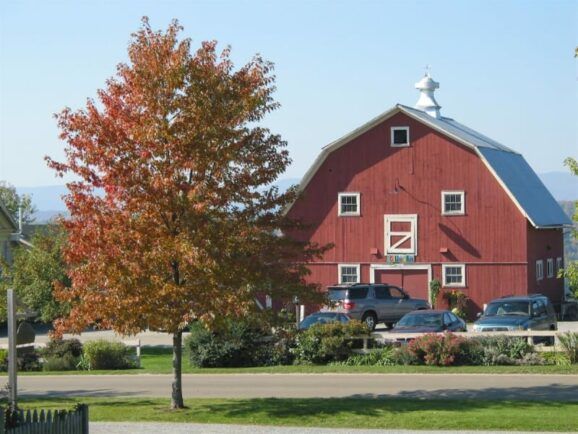 A red barn with cars parked in front of it