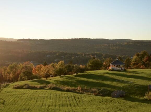 A house is sitting on top of a hill in the middle of a field.