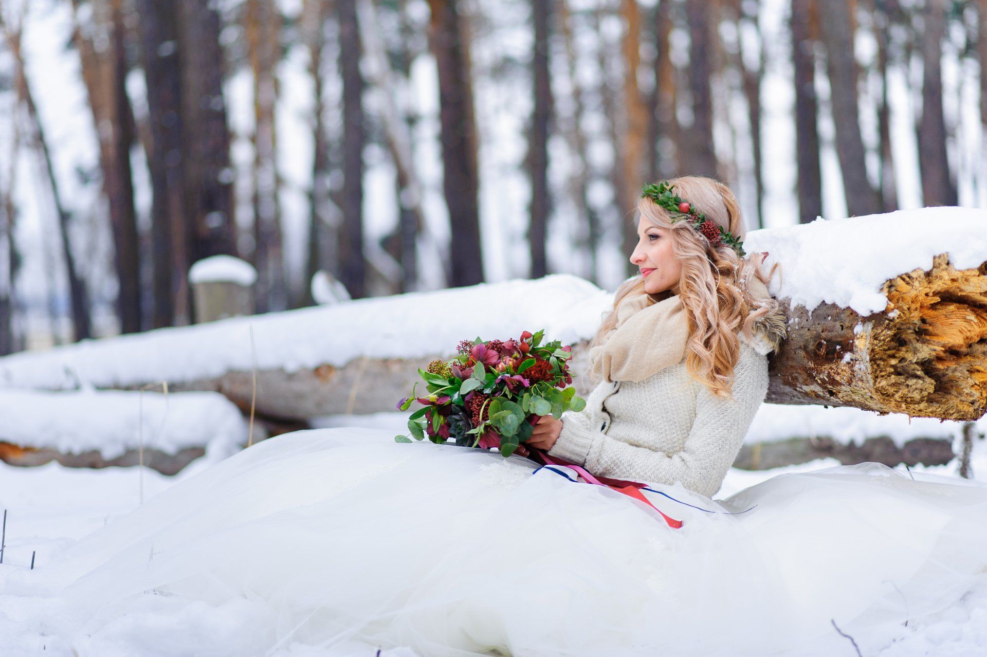 Winter Bride holding a red and green bouquet of flowers surrounded by snow