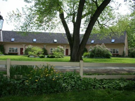 A house with a white fence and a tree in front of it