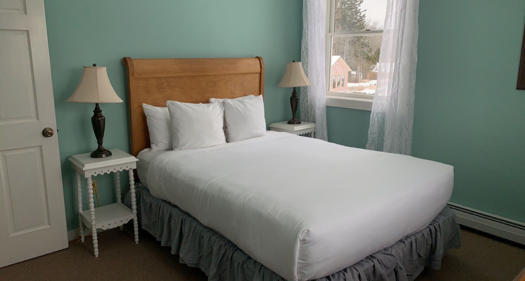 A bedroom with a bed , two lamps and a window.