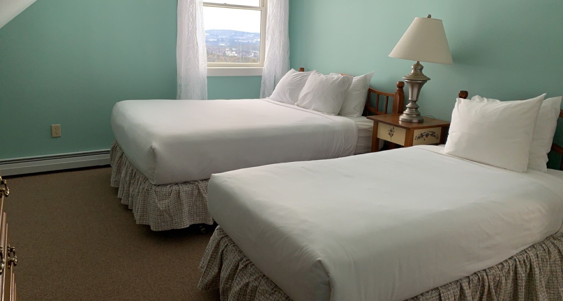 A hotel room with two beds and a lamp