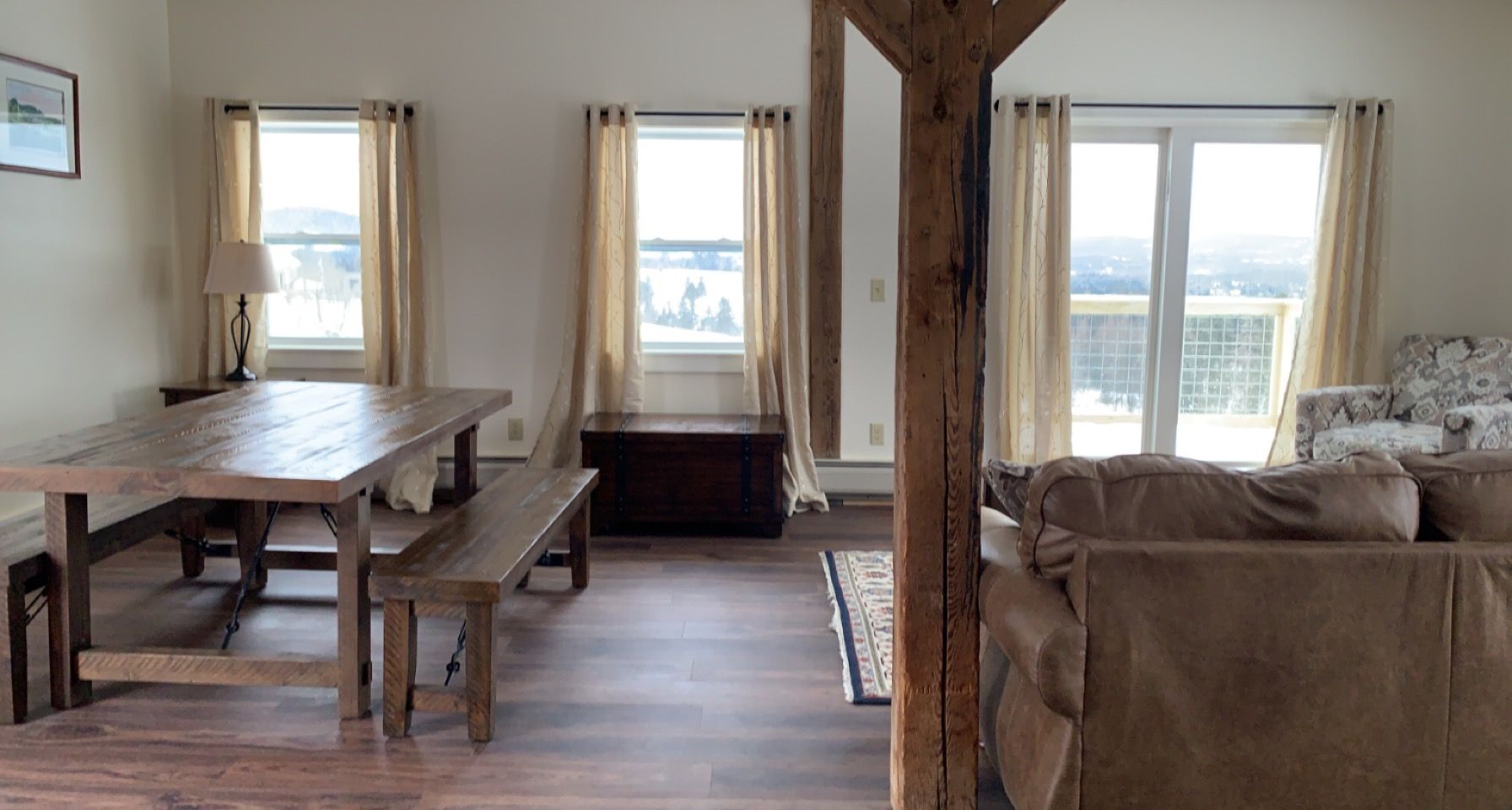 A living room with a couch , table , bench and windows.