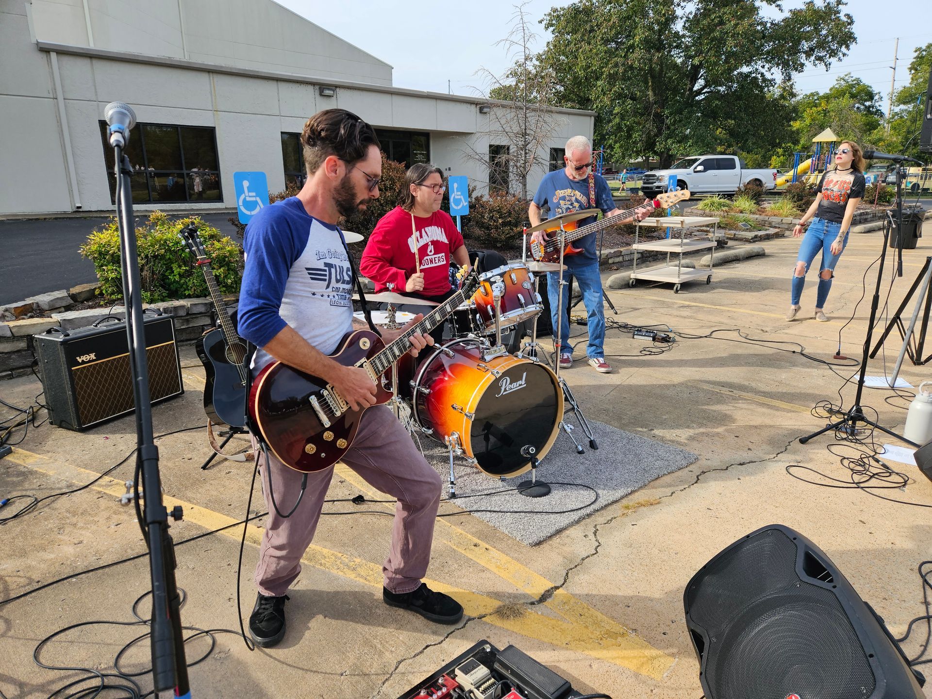 A group of people are playing instruments in a parking lot.
