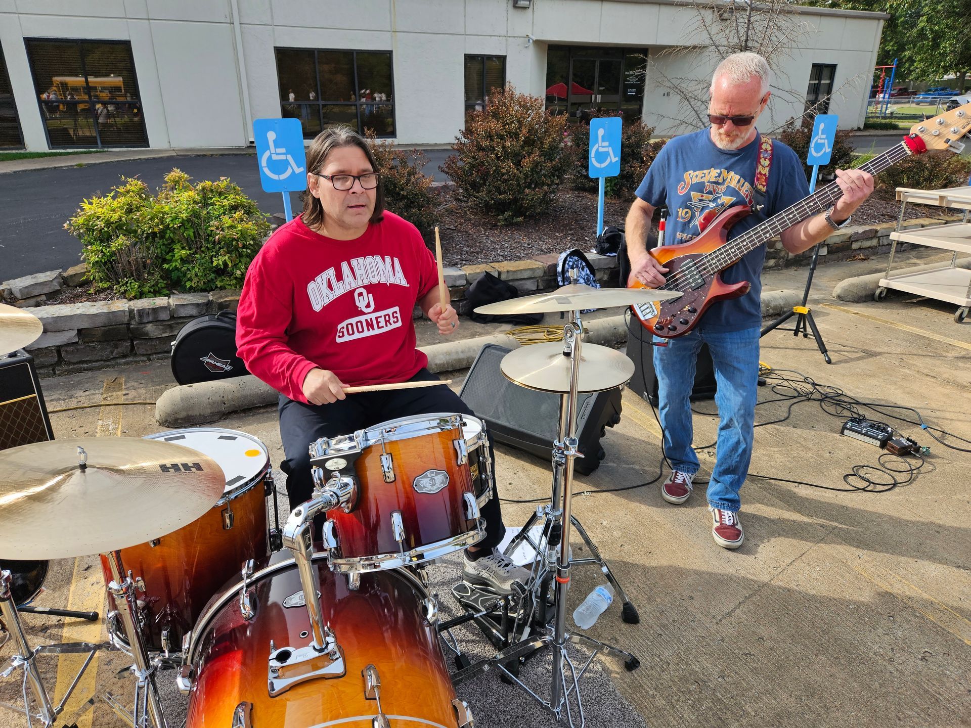 A man is playing a guitar and a woman is playing drums.