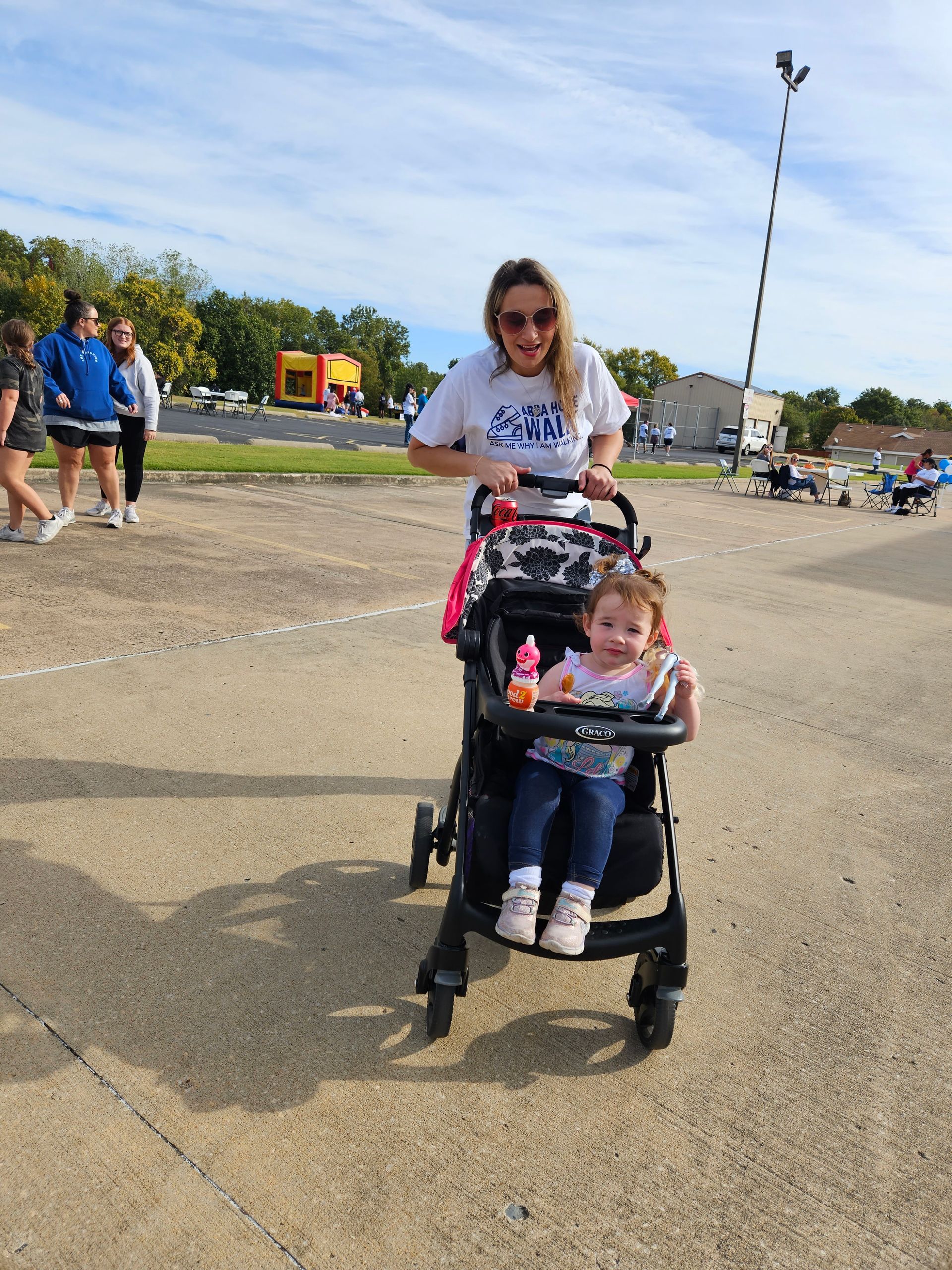 A woman is pushing a stroller with a little girl in it.