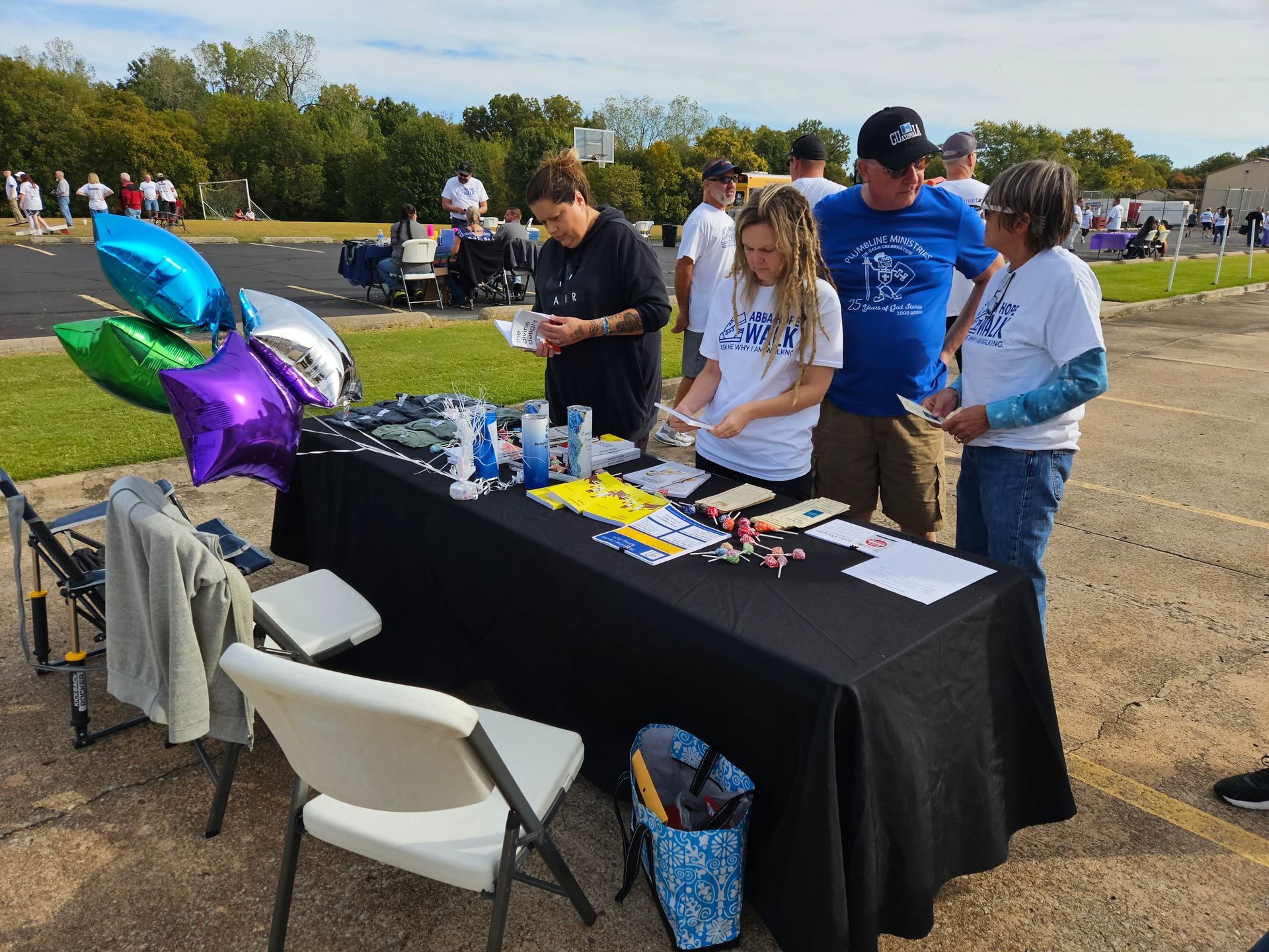 A group of people are standing around a table with balloons on it.