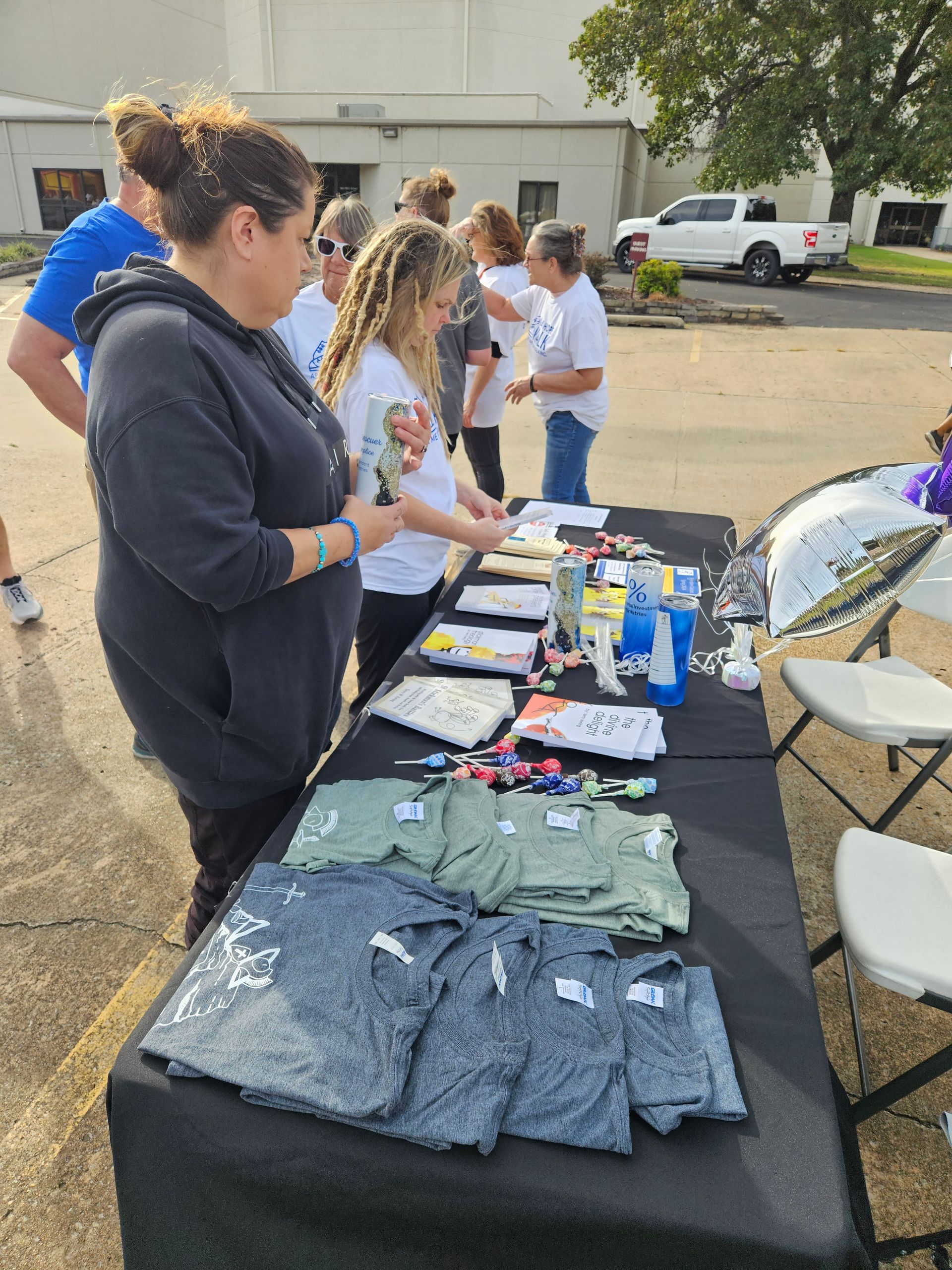 A group of people are standing around a table with shirts on it.