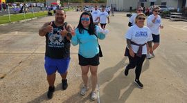 Abba Walk 2023 group of people are walking down a street and giving thumbs up.