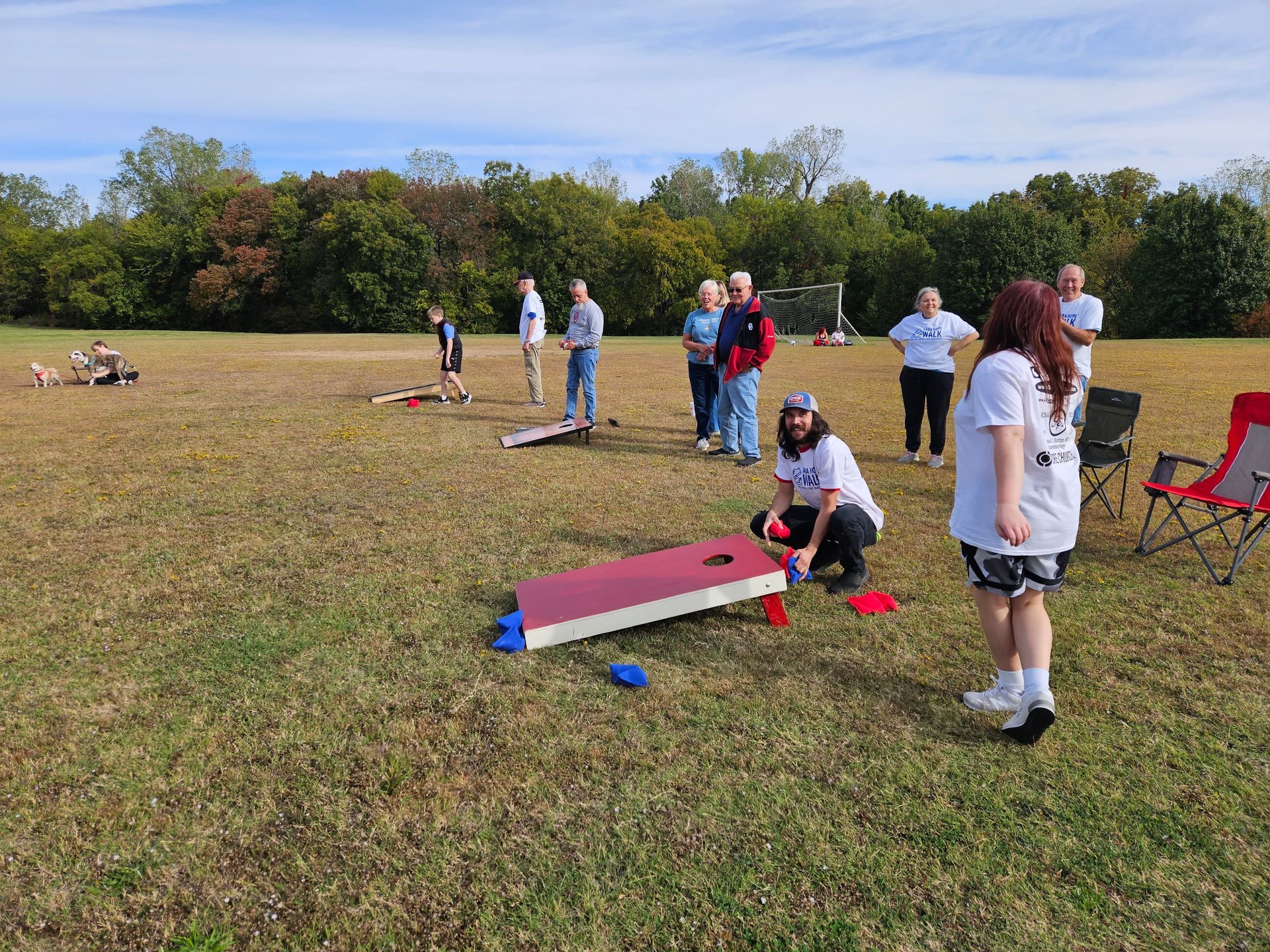 A group of people are playing cornhole in a field.