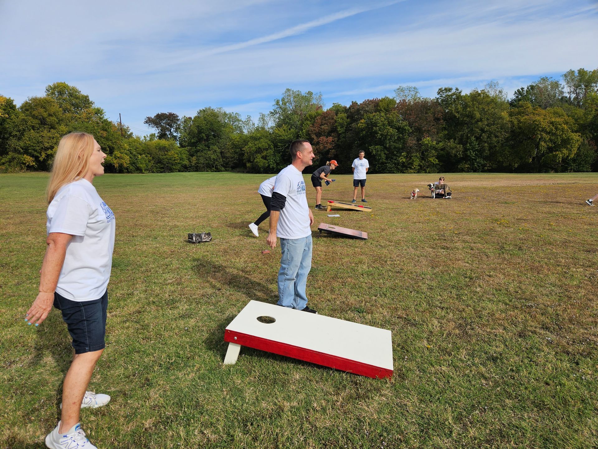 A group of people are playing cornhole in a field.