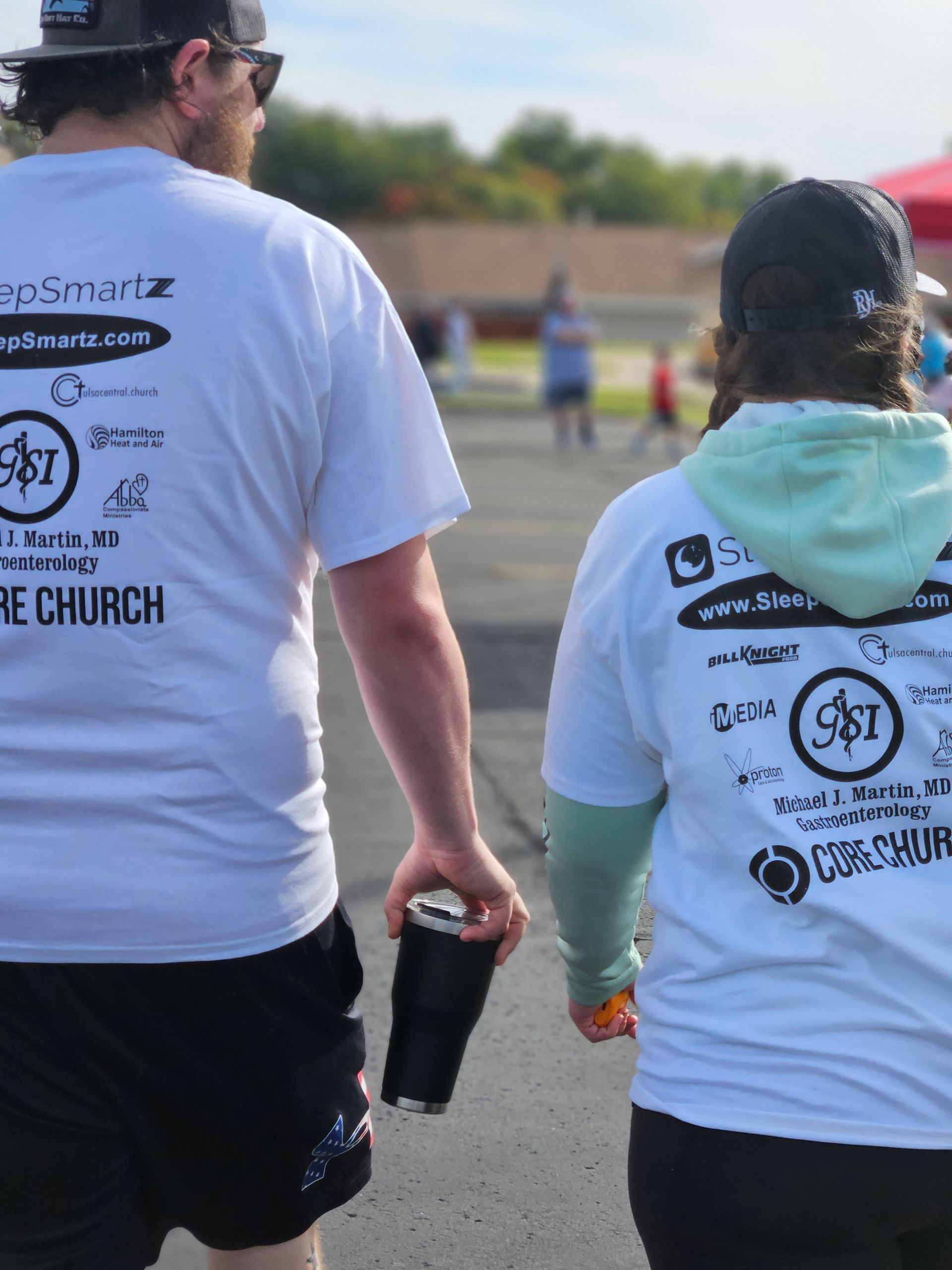 A man and a woman are walking down the street holding hands.