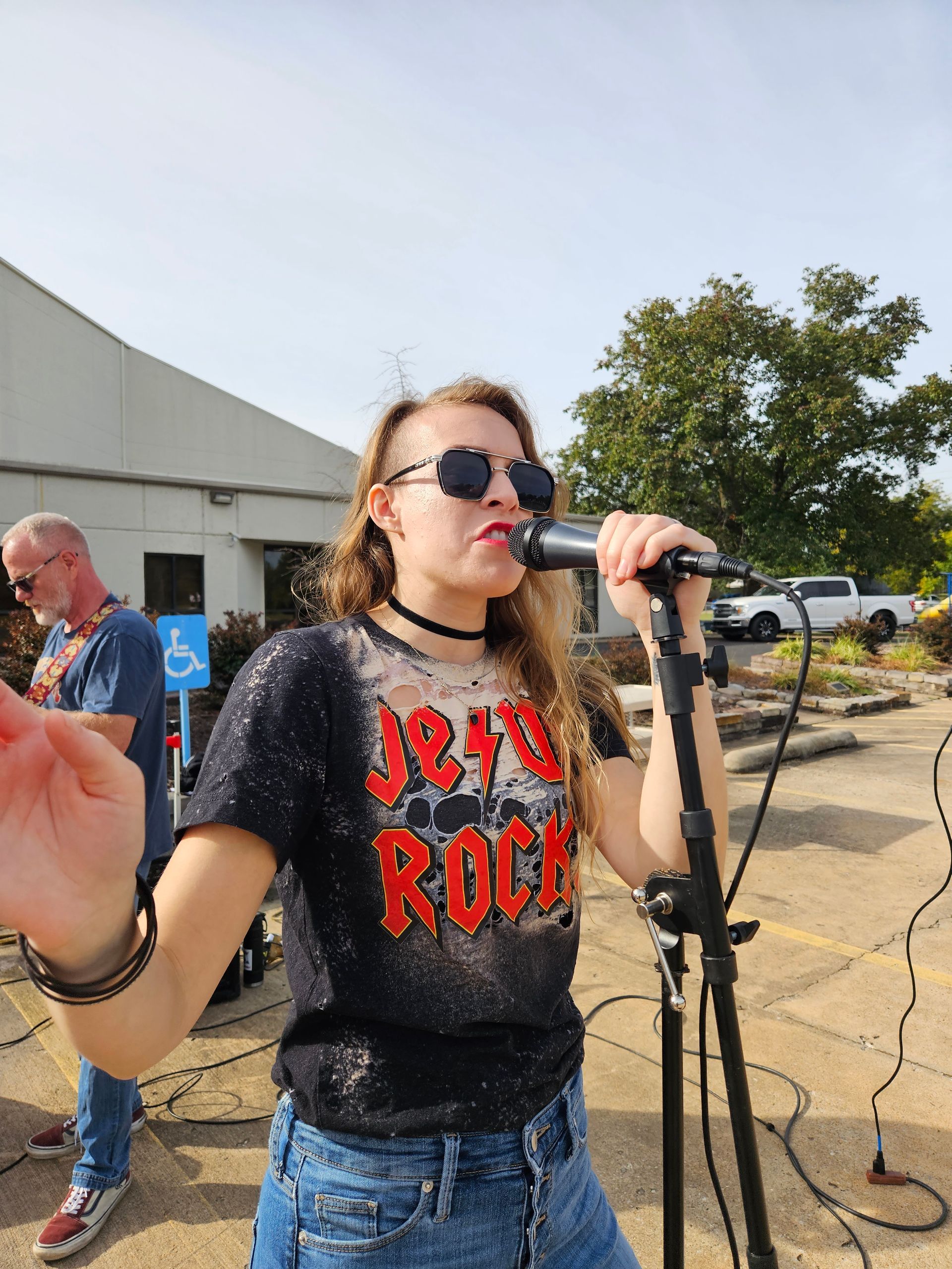 A woman singing into a microphone wearing a jesus rock shirt