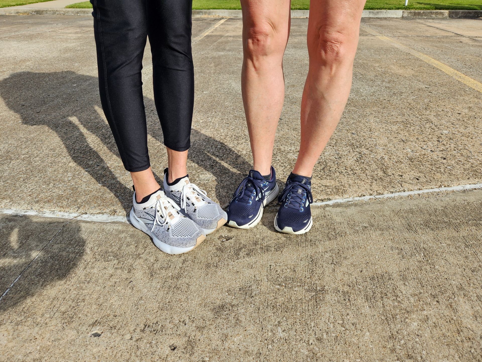 Two women are standing next to each other wearing sneakers.