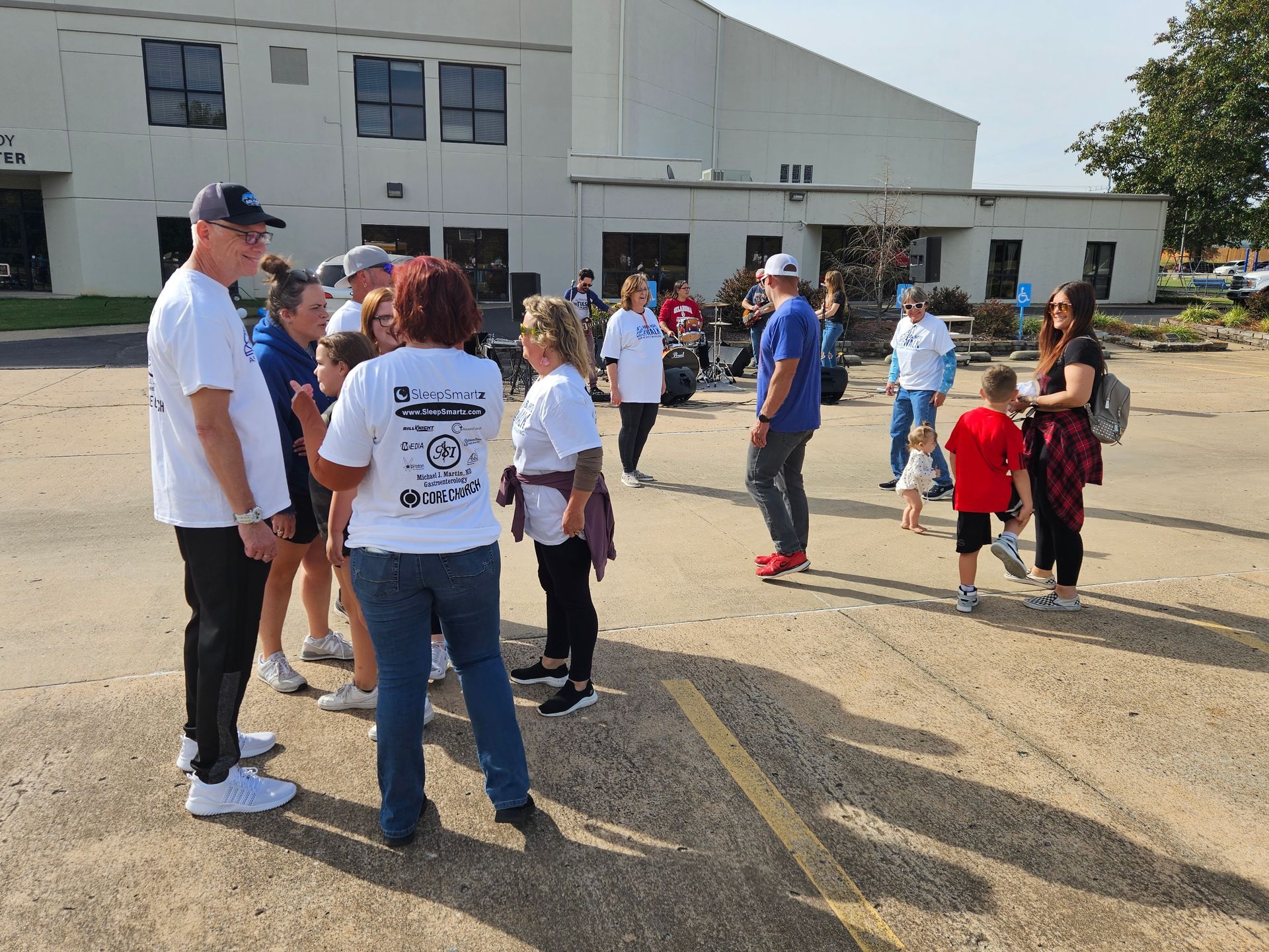 A group of people are standing in a parking lot in front of a building.