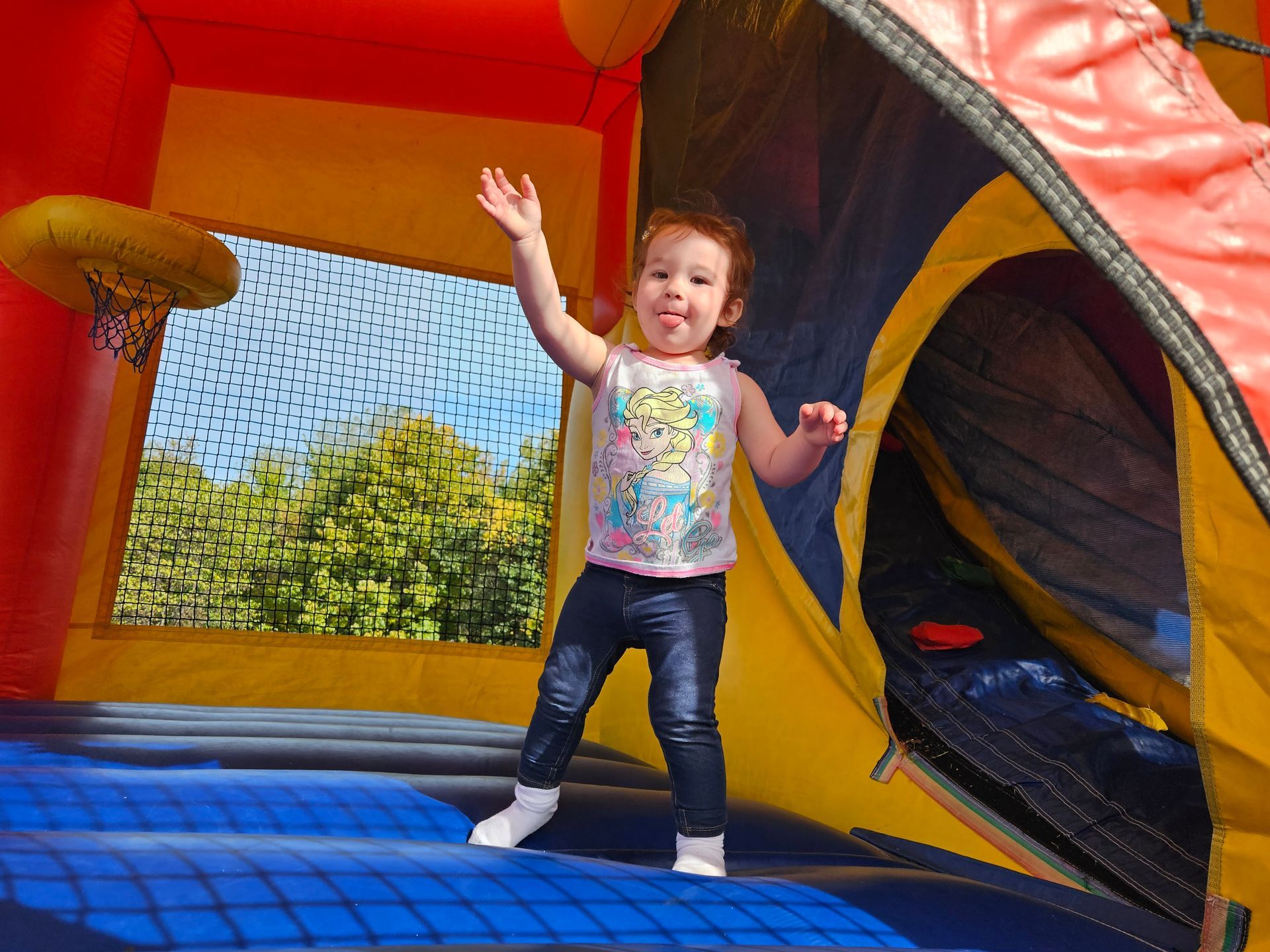 A little girl is standing on top of a bouncy house.