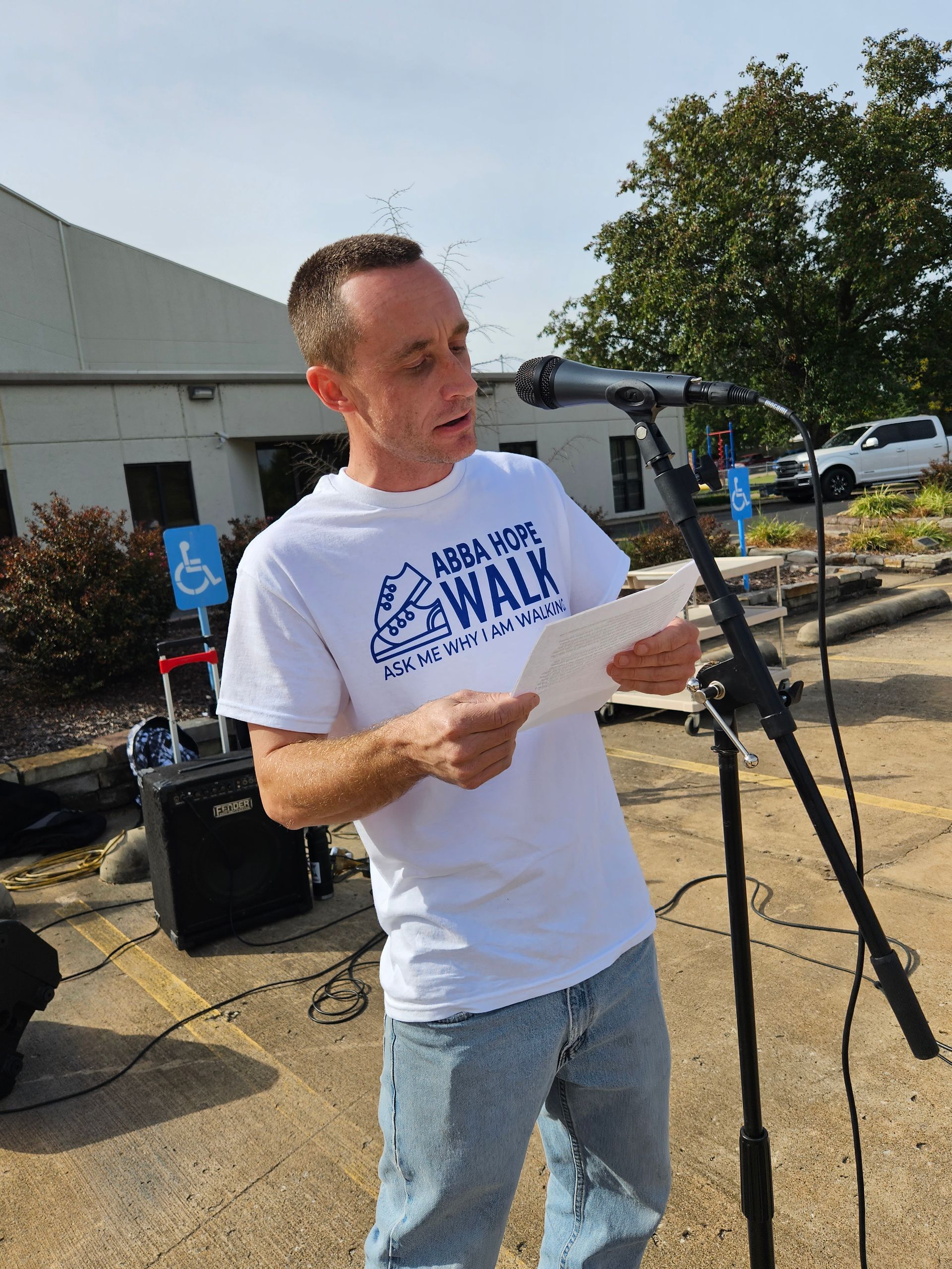 A man is standing in front of a microphone holding a piece of paper.