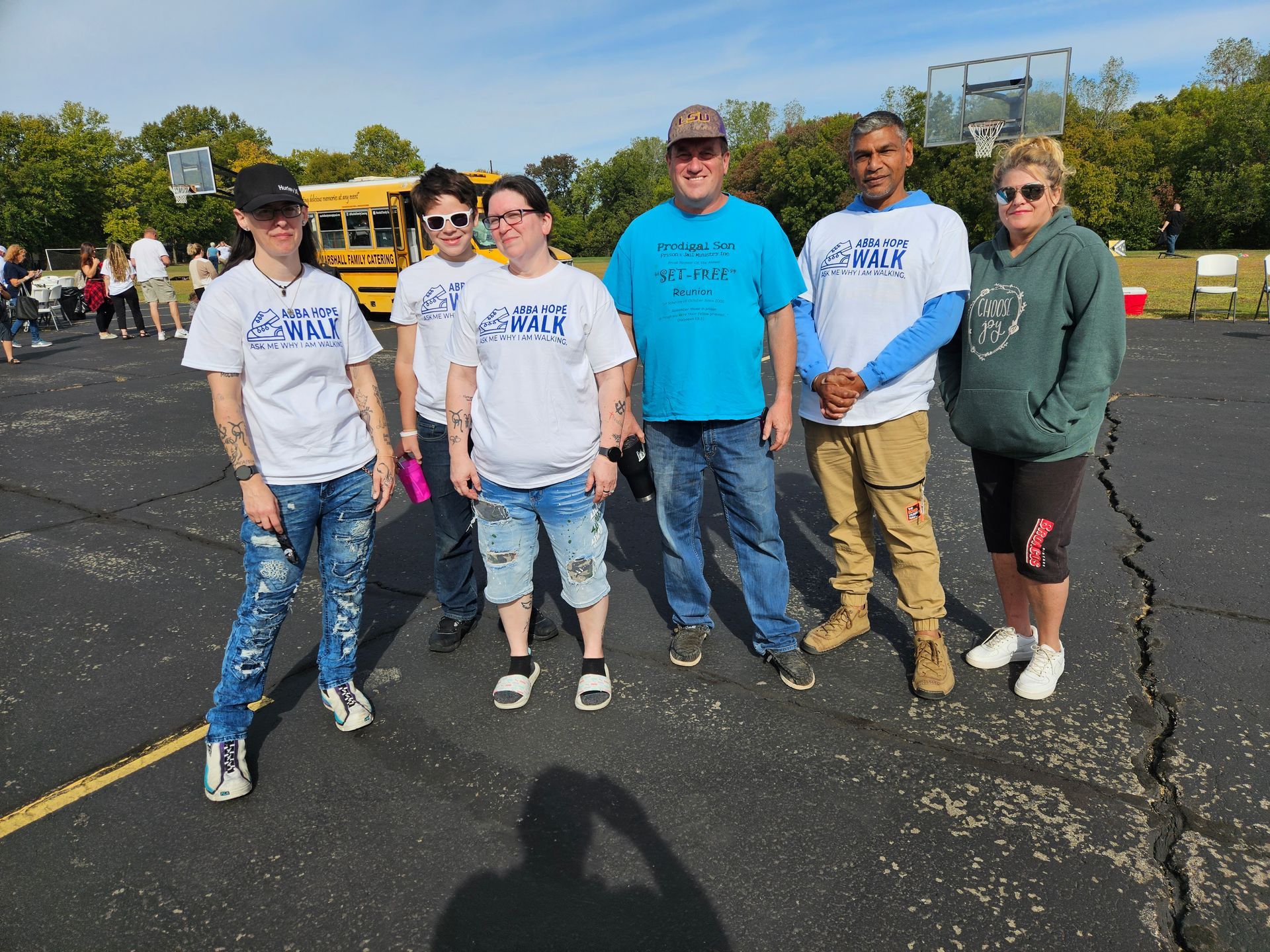 A group of people standing in a parking lot with a school bus in the background