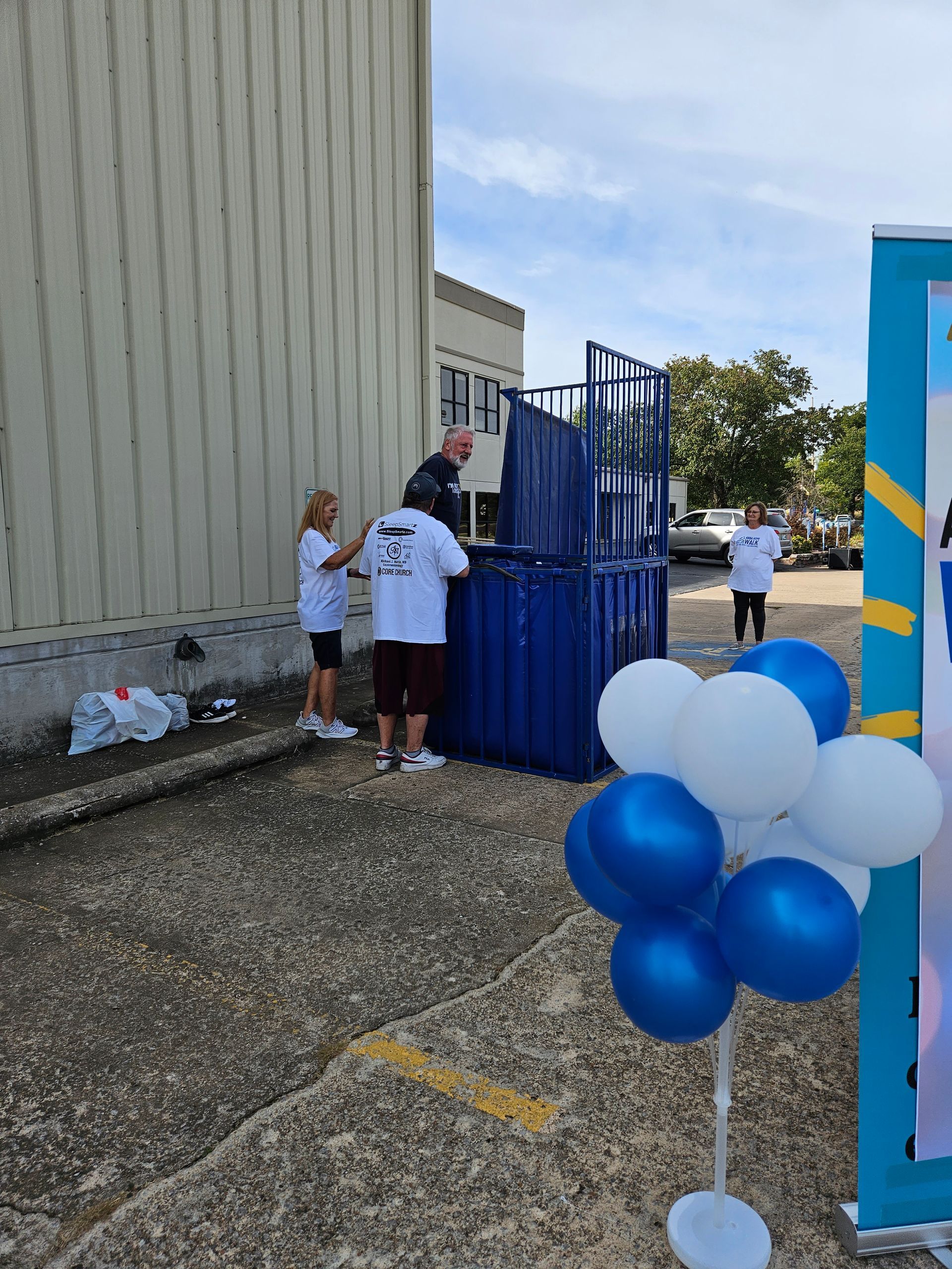 A group of people are standing in front of a blue and white balloon display.