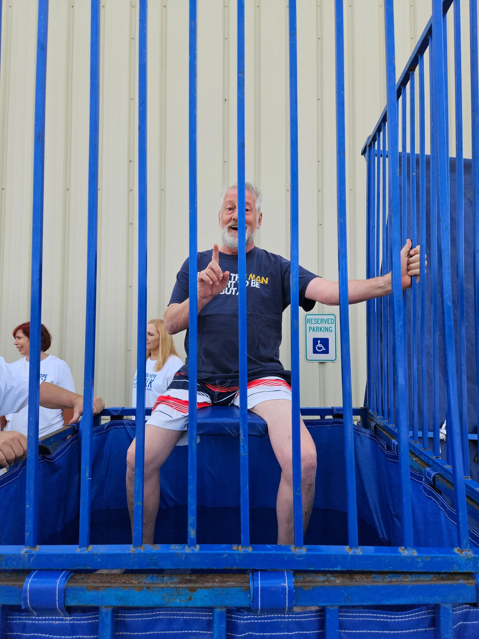A man in a black shirt is sitting in a blue cage