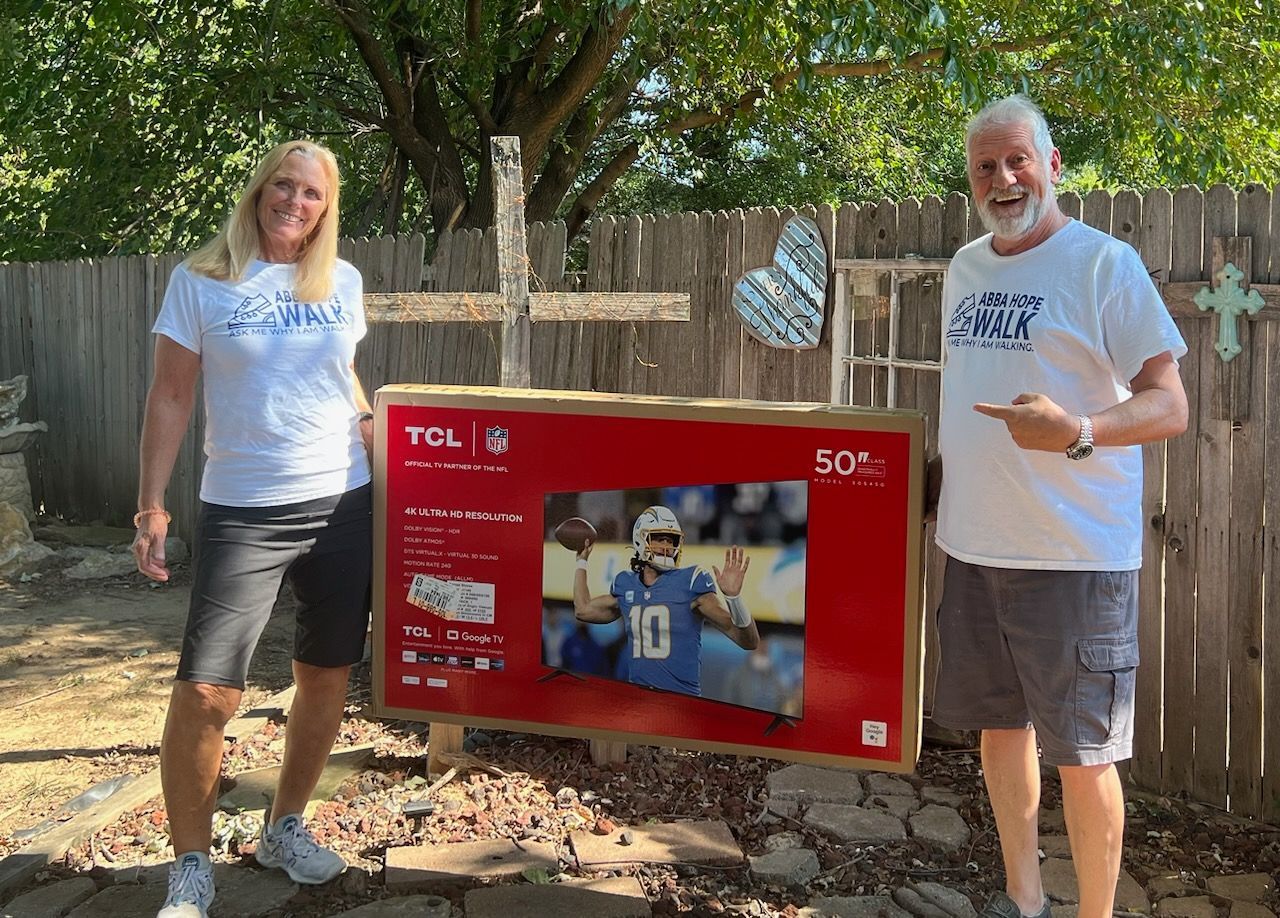 A man and a woman are standing next to a tcl television.