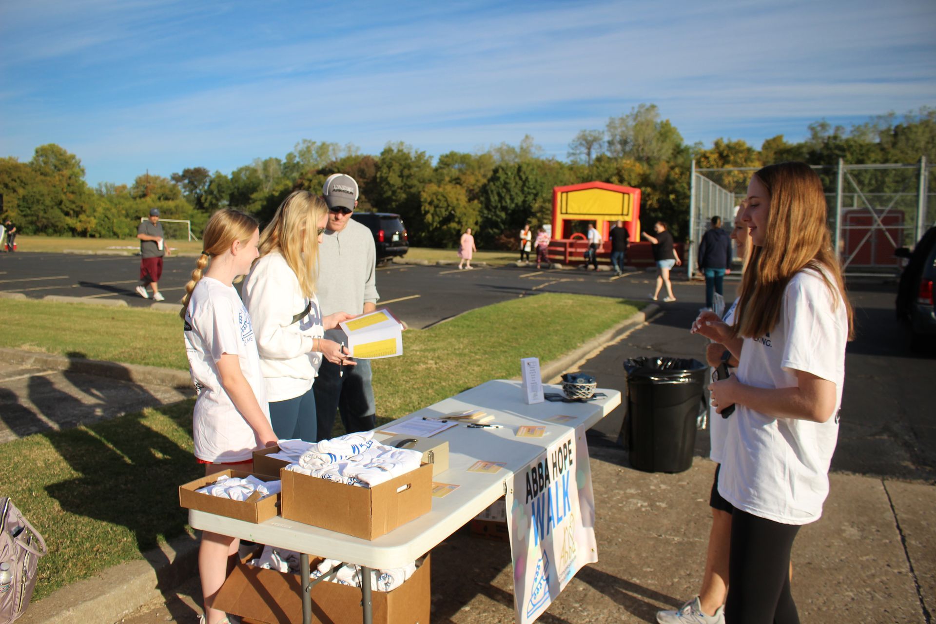 A group of people are standing around a table in a parking lot.