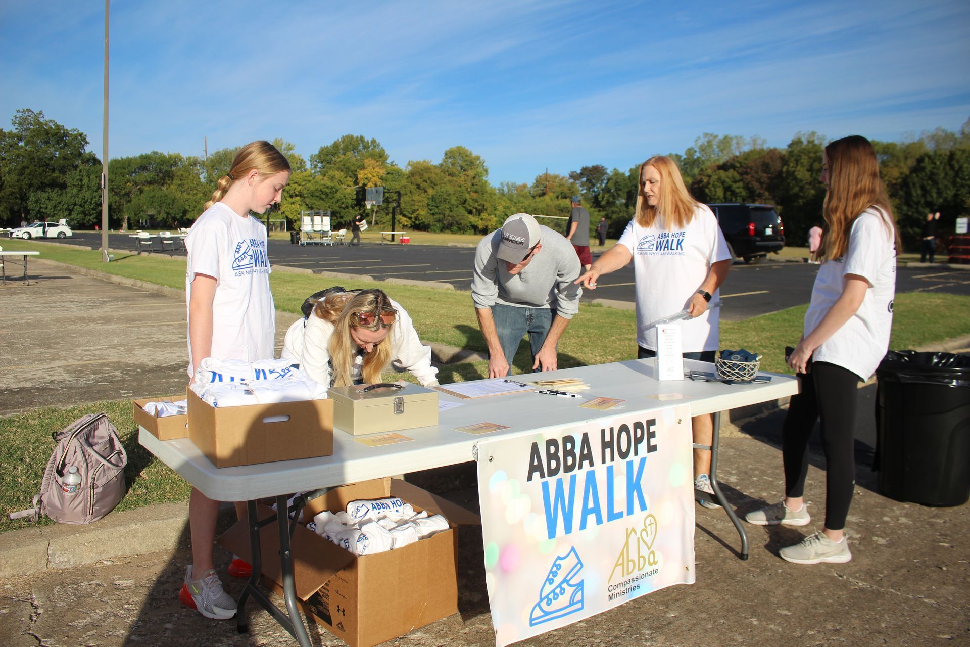 A group of people are standing around a table with a sign that says abba hope walk.
