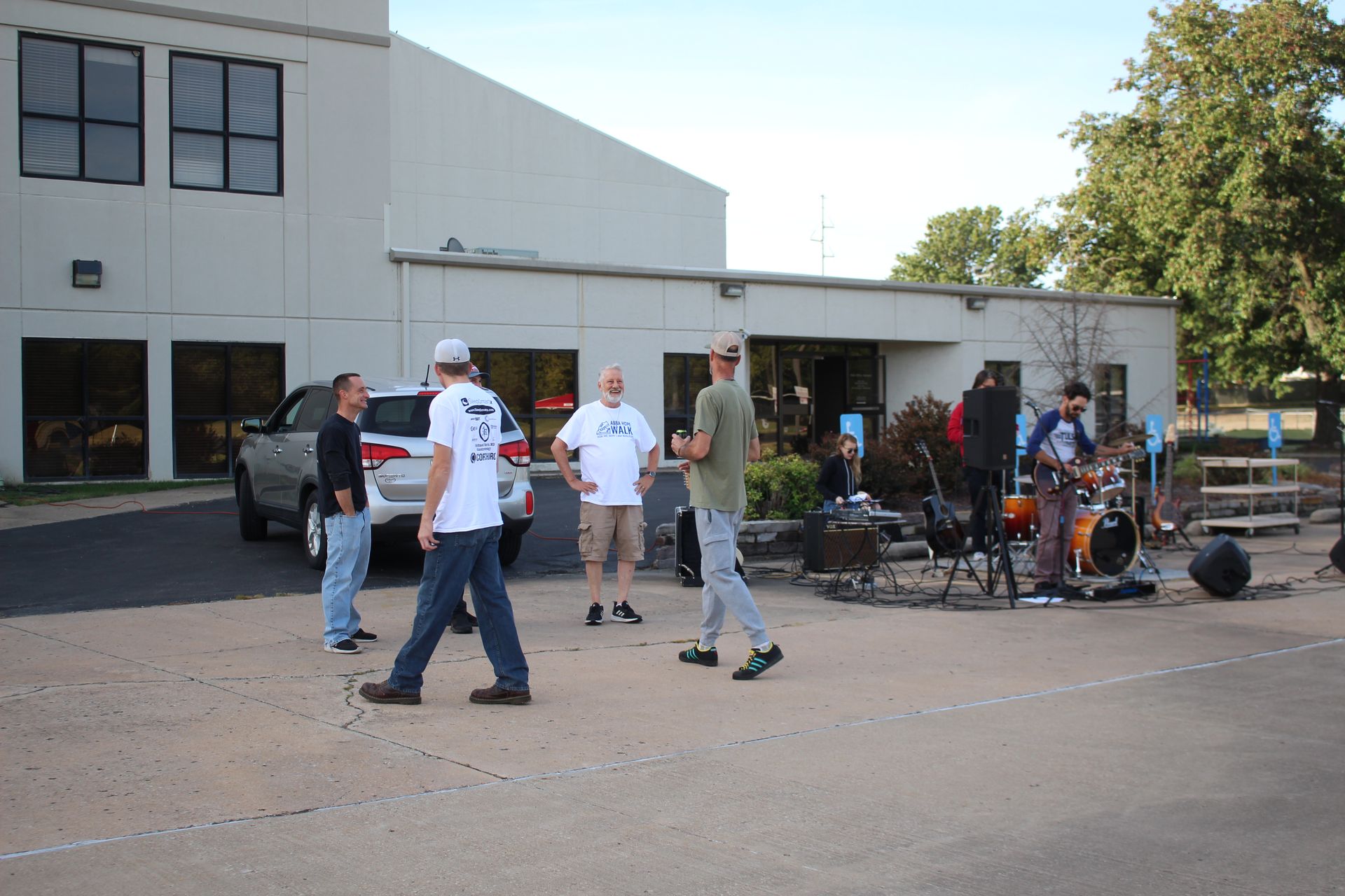 A group of men are standing in a parking lot in front of a building