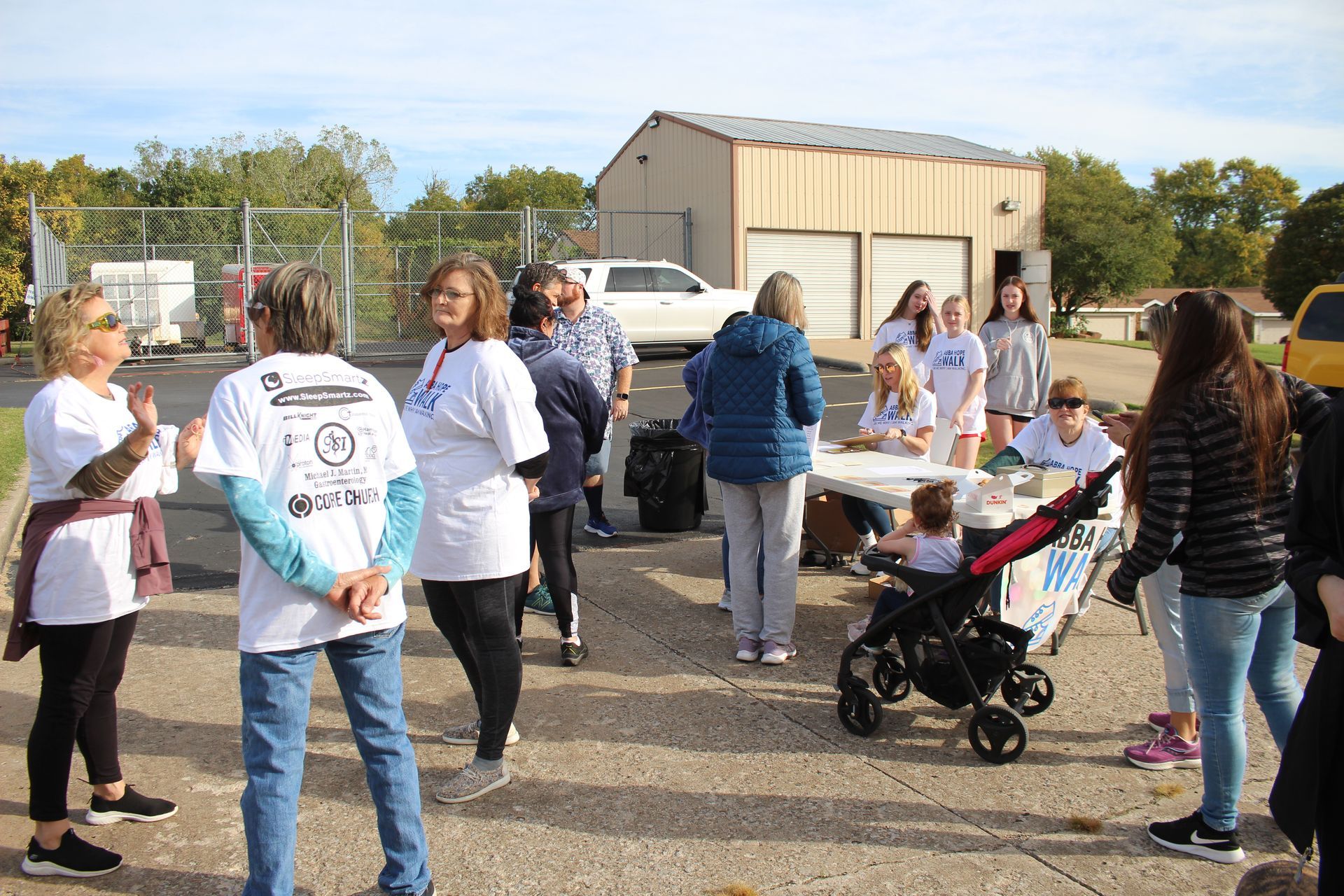 A group of people are standing around a table in a parking lot.