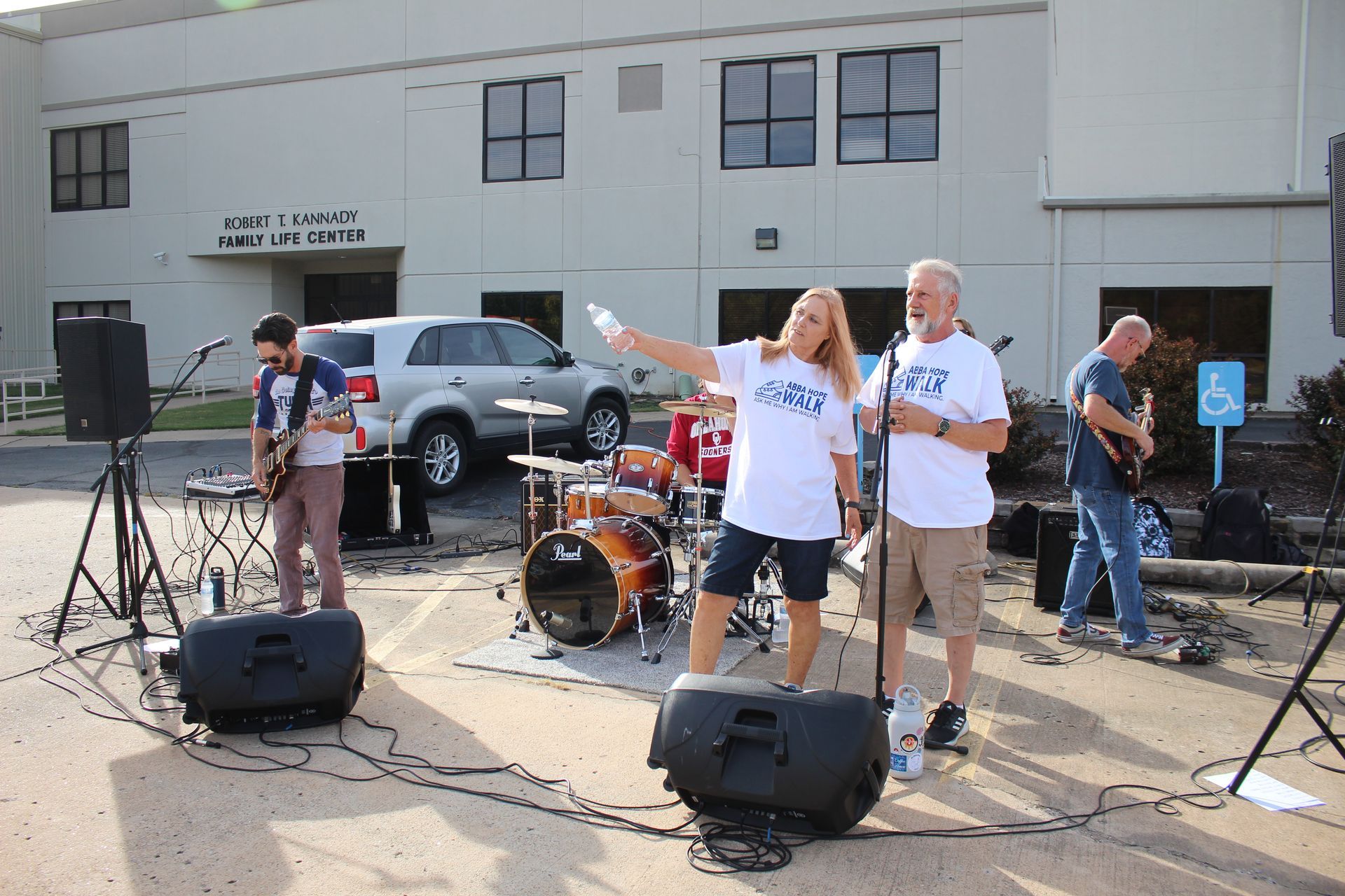 A group of people are playing music in front of a building with a handicap sign
