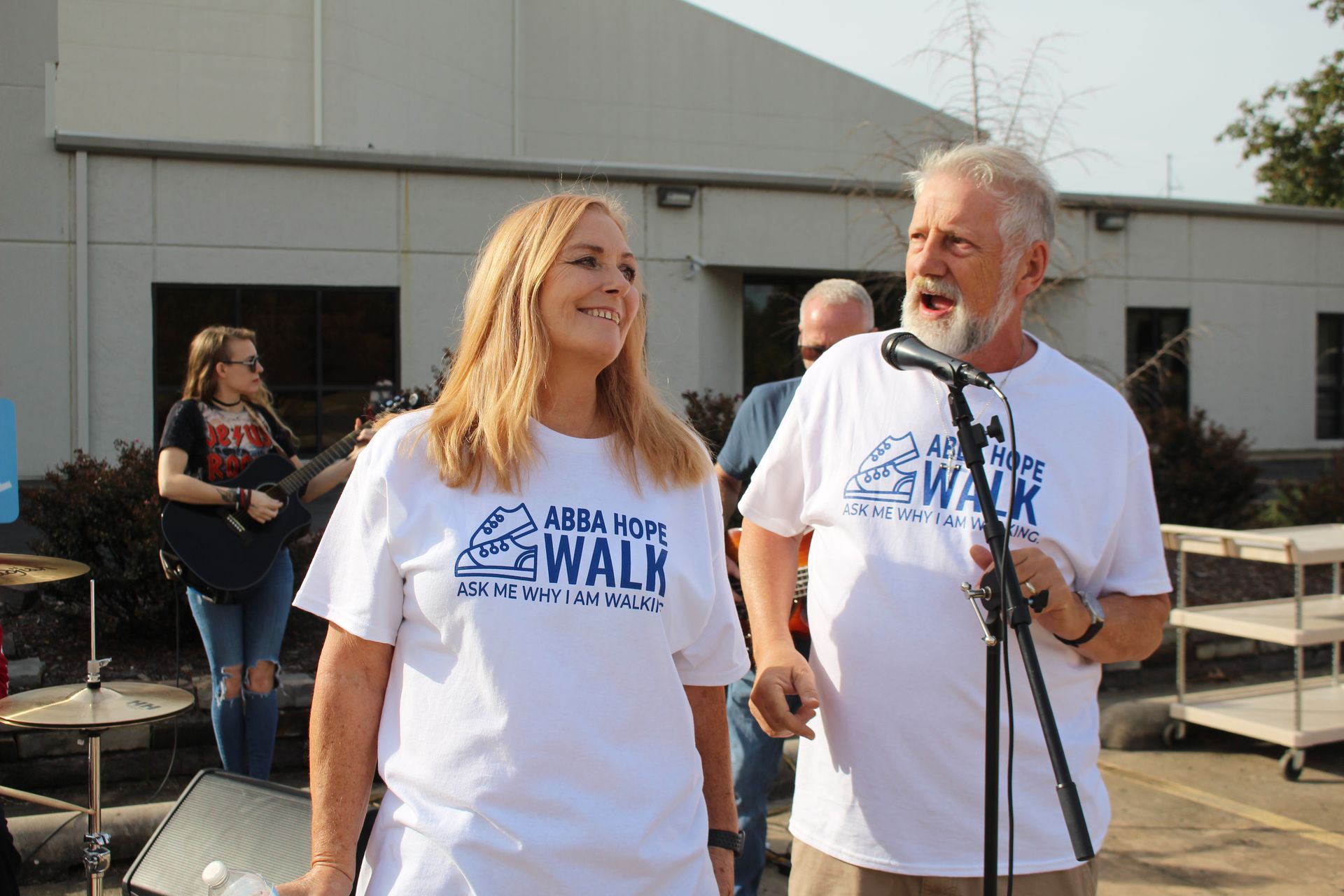 A man and a woman are standing in front of a microphone.