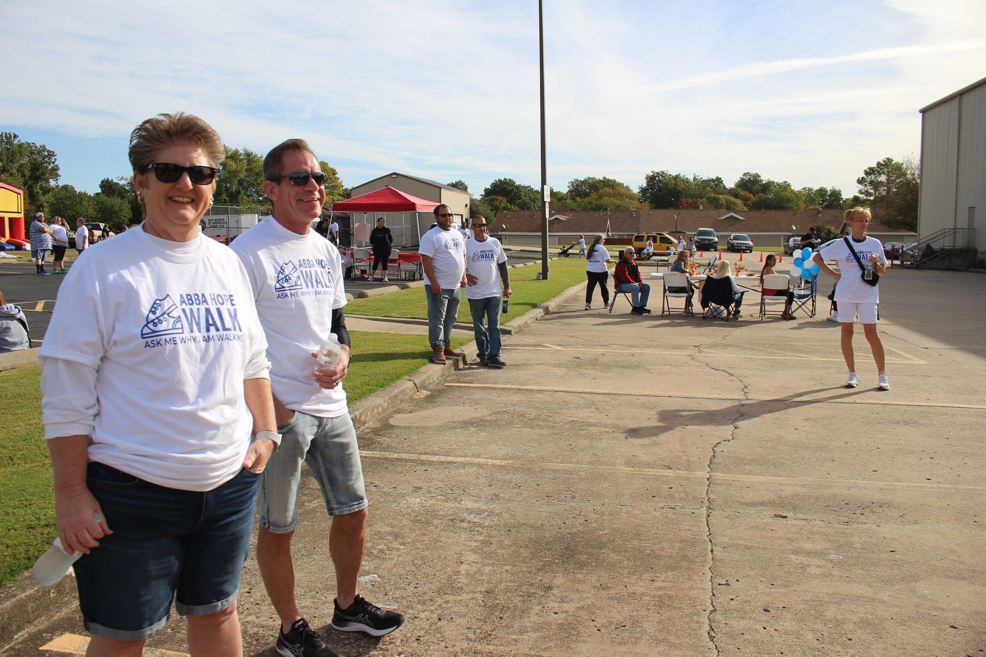 A group of people standing on a sidewalk wearing white shirts that say sunday