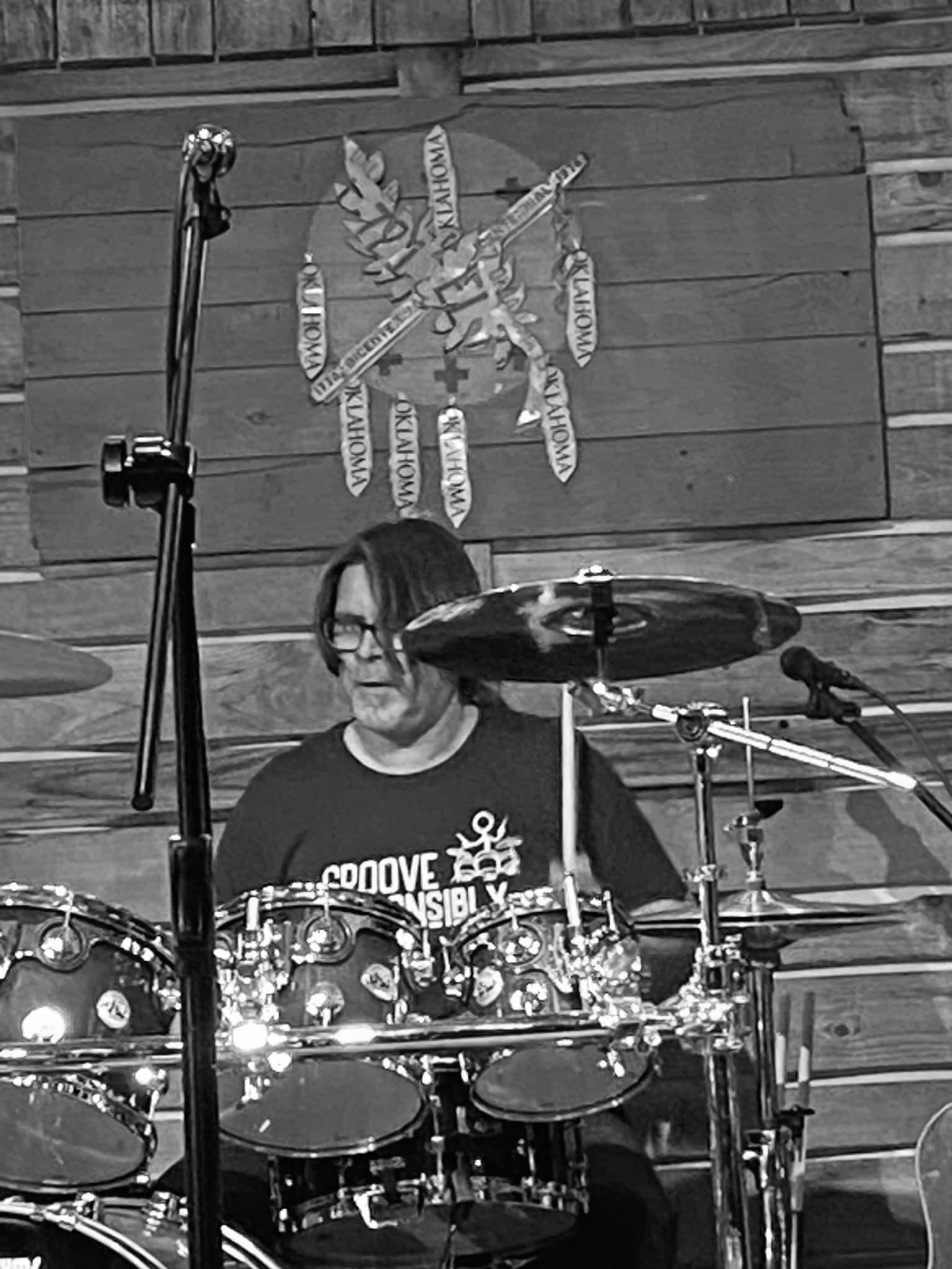 A man is playing drums in a black and white photo.