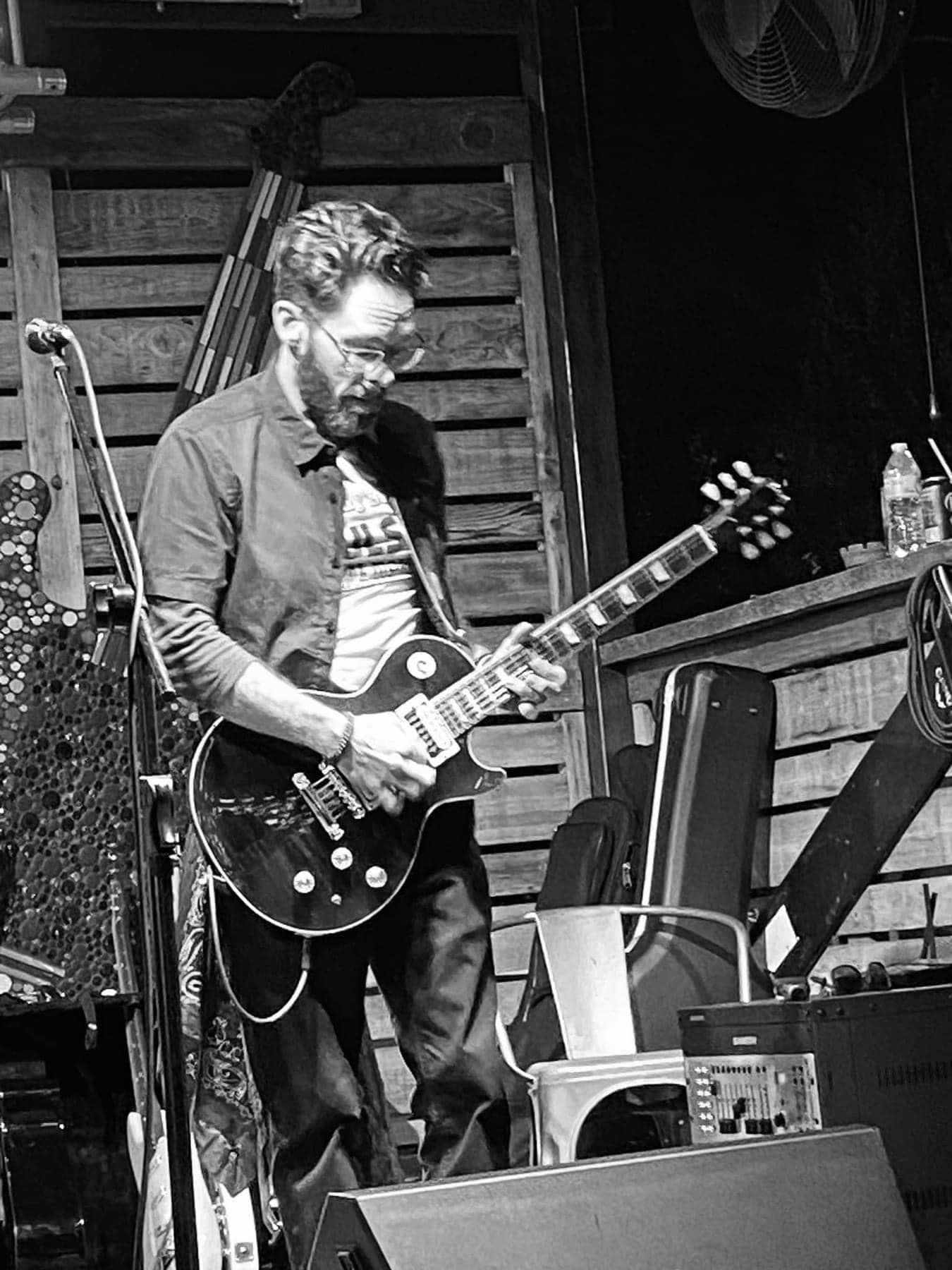 A man is playing a guitar on a stage in a black and white photo.