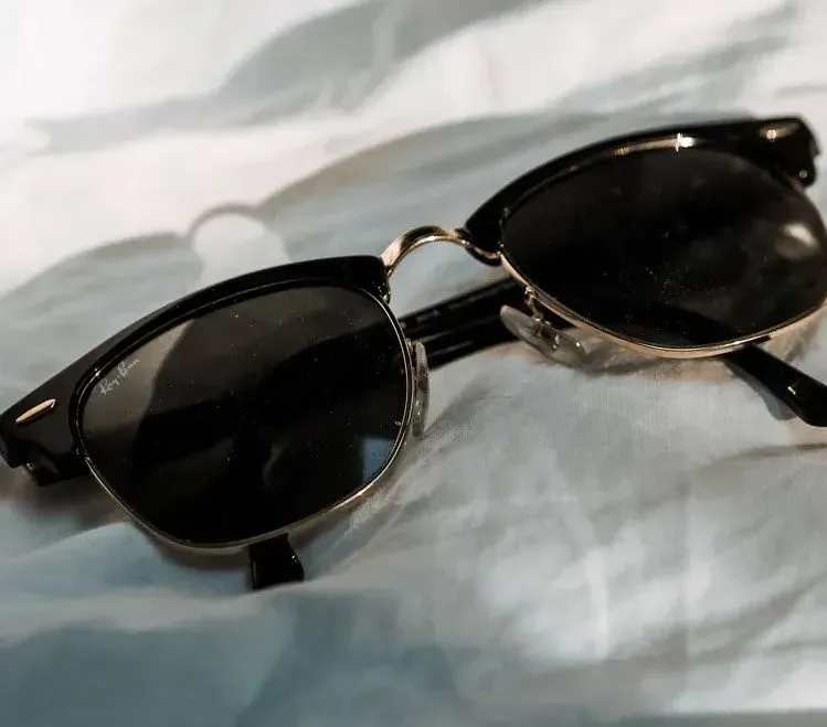 A pair of ray-ban sunglasses laying on a white cloth