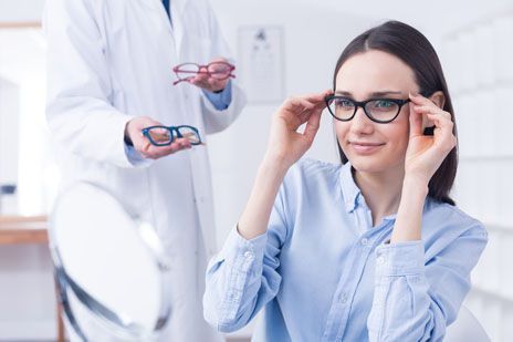 A woman is trying on glasses in front of an ophthalmologist.