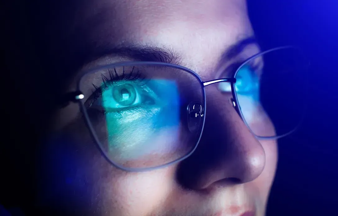 A woman wearing glasses is looking at a computer screen.