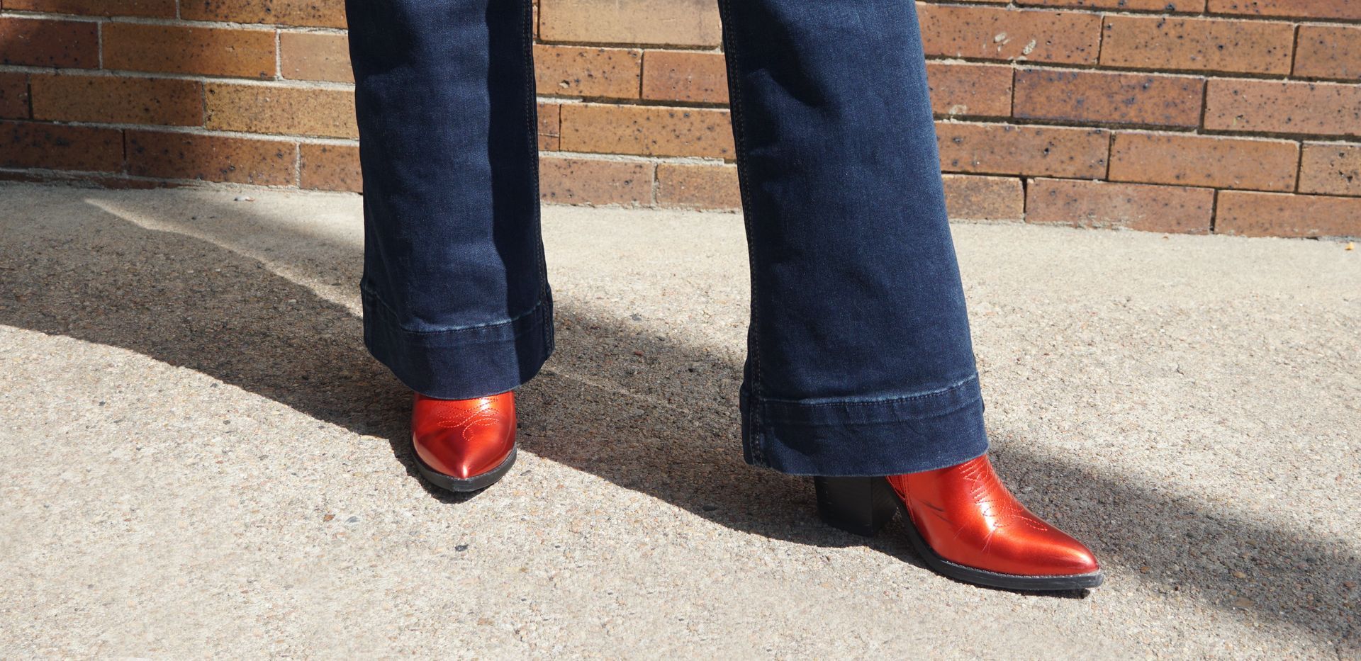 A person wearing red cowboy boots and blue jeans