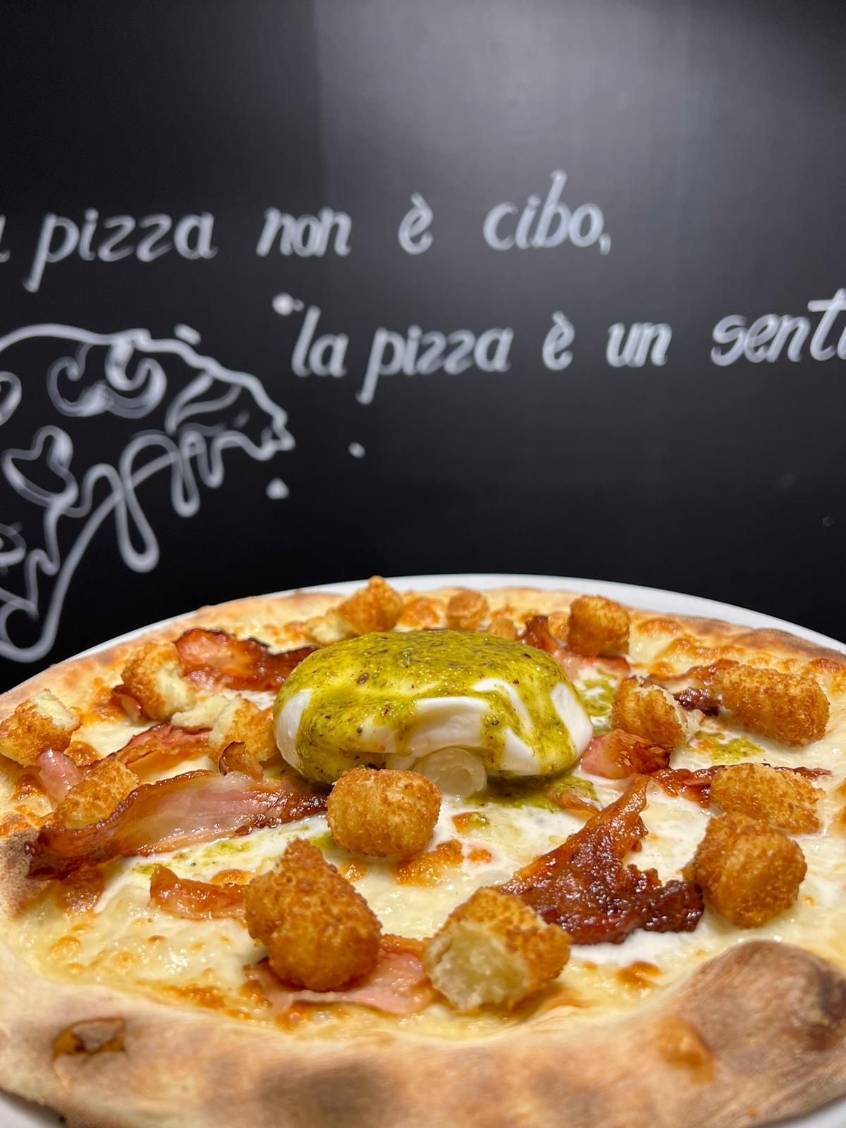 Una pizza è su un piatto davanti a una lavagna che dice pizza non e cibo