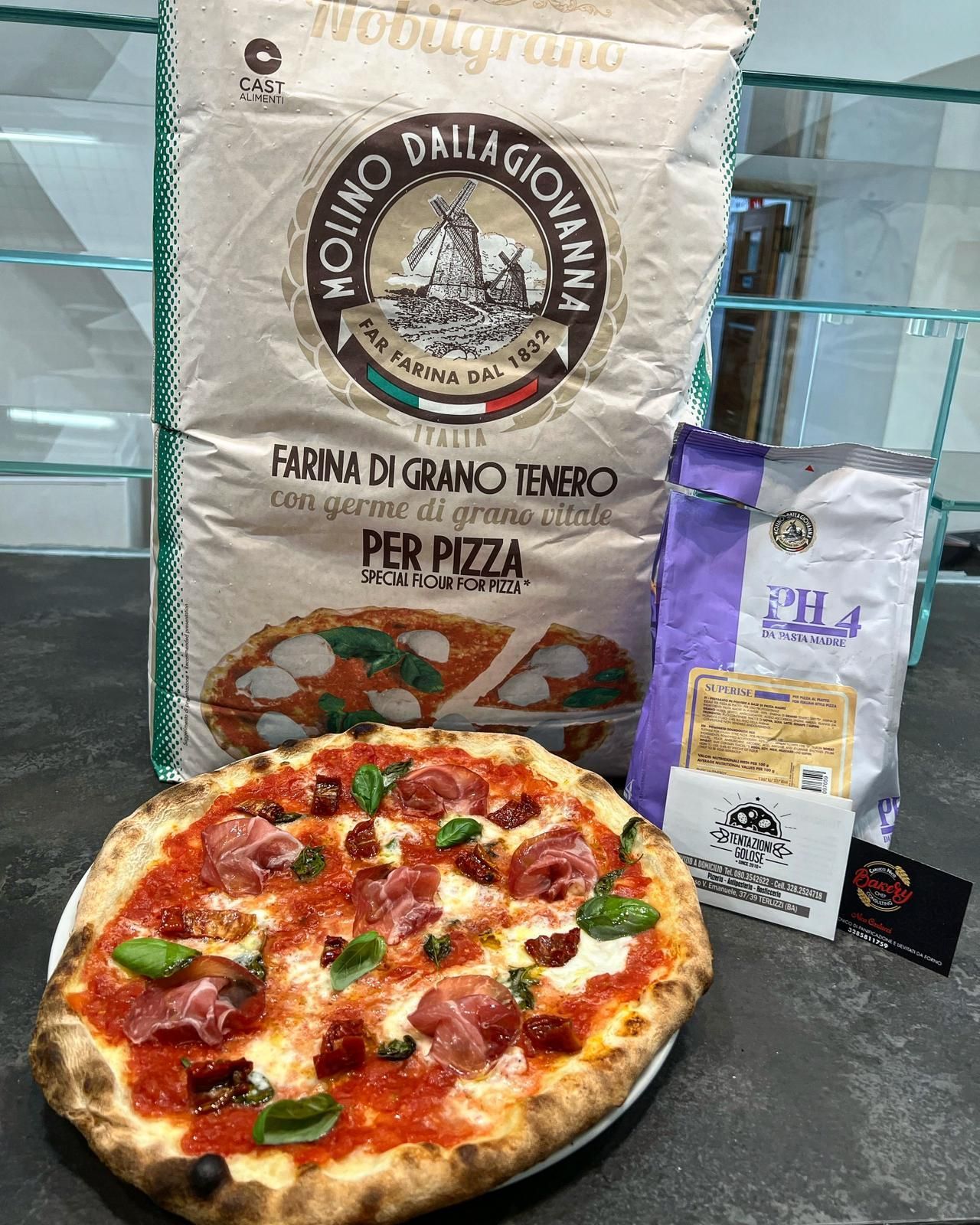 Una pizza è appoggiata su un piatto accanto a un sacco di farina.