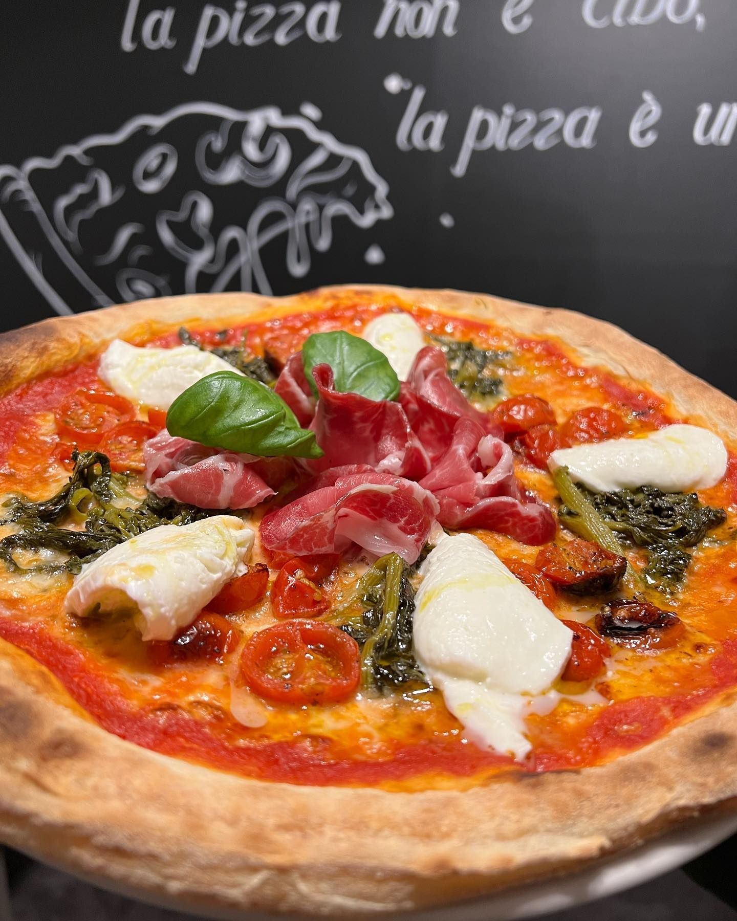 Una pizza è su un piatto davanti a una lavagna che dice la pizza