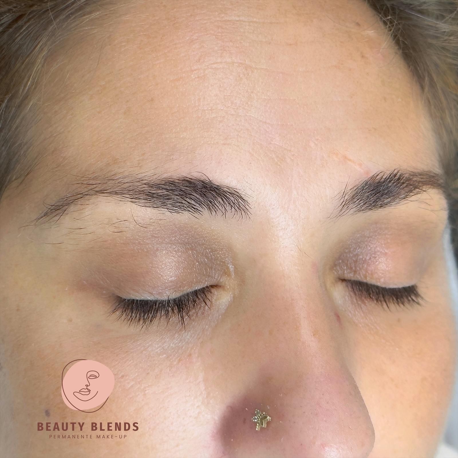 Vrouw met gesloten ogen, na microblading van de wenkbrauwen; lichte huidskleur.