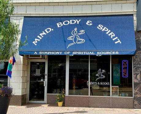 A store front with a blue awning that says mind body and spirit